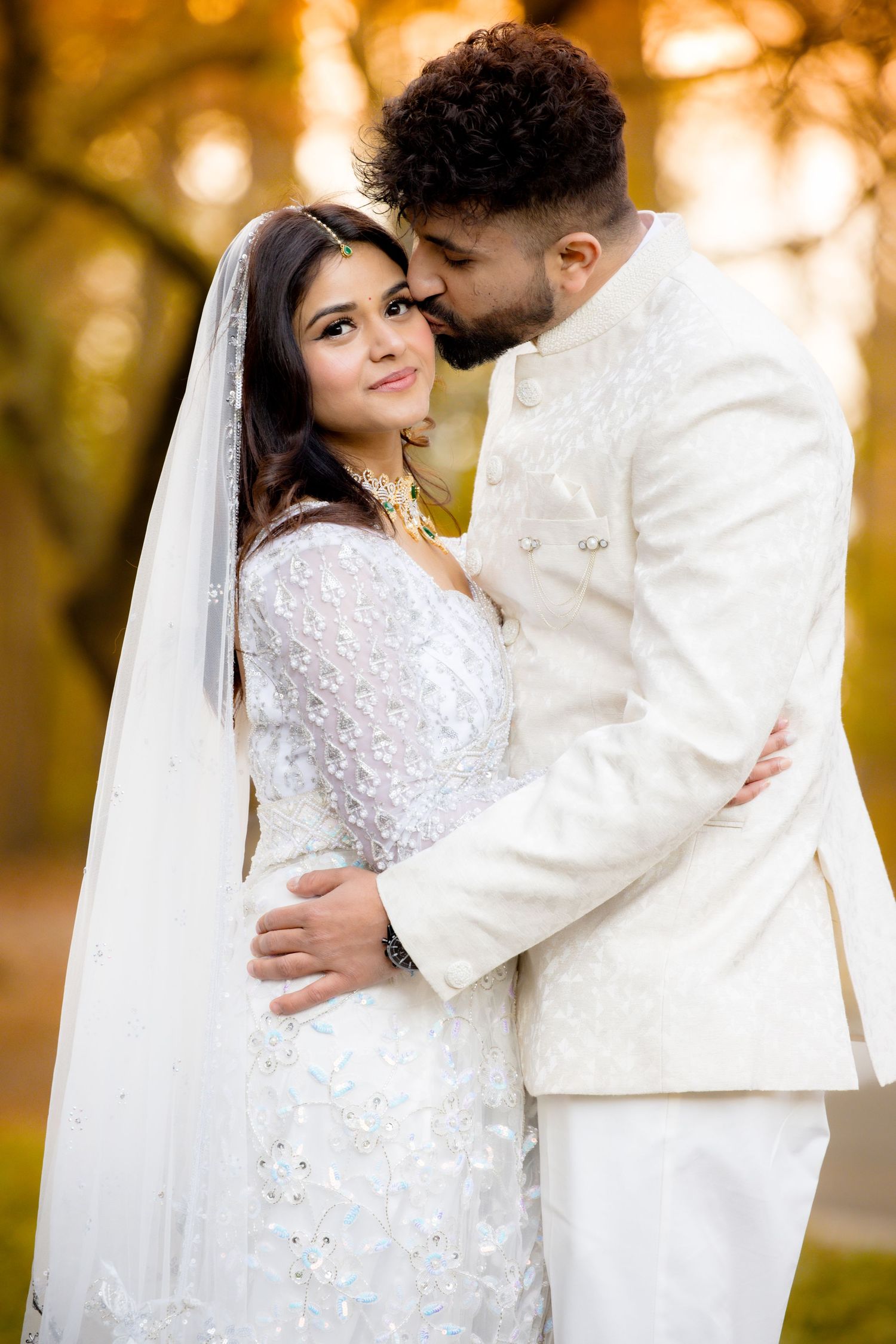 An intimate outdoor wedding portrait with warm autumn colors in the background.