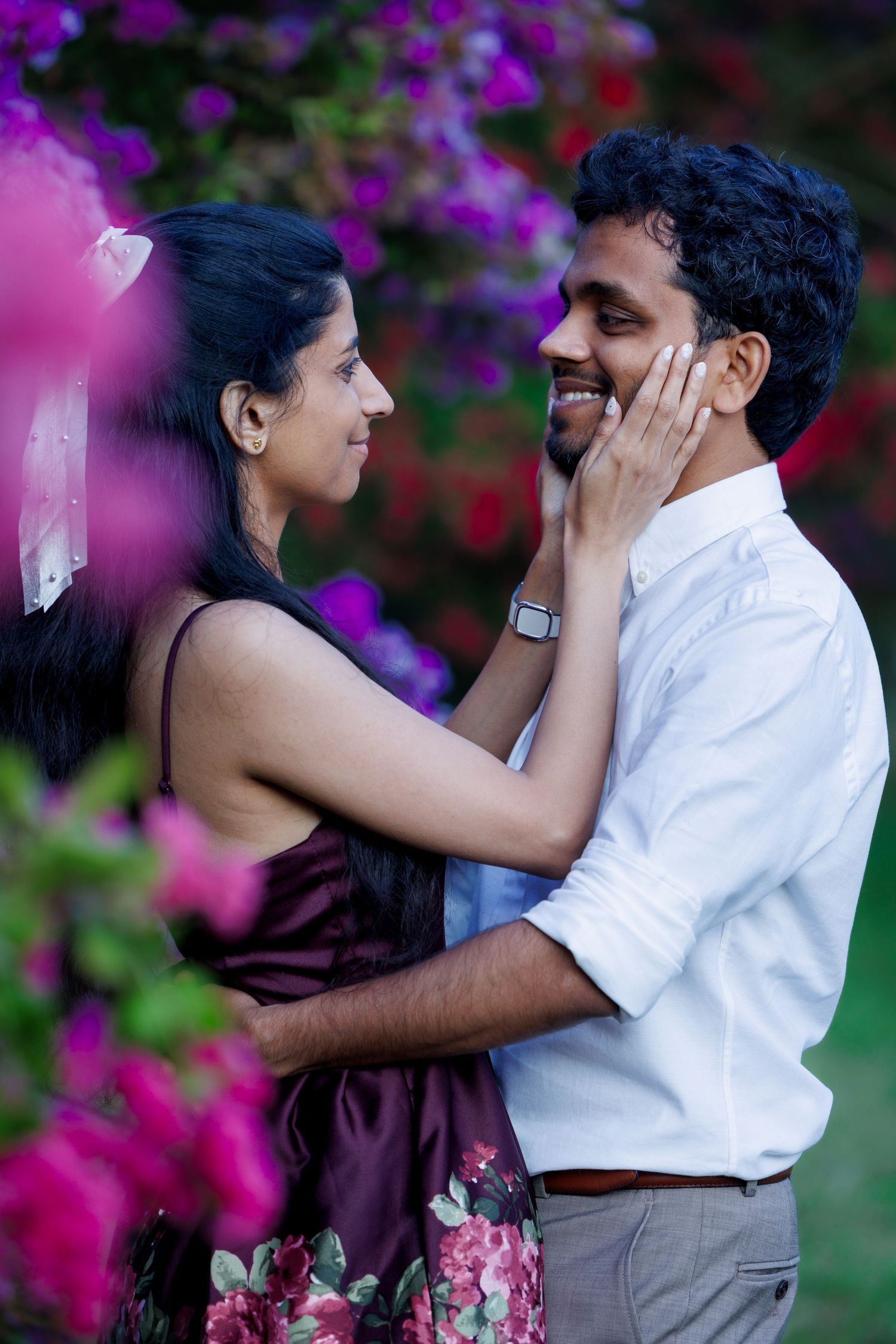 Intimate moment between couple surrounded by vibrant purple bougainvillea flowers.