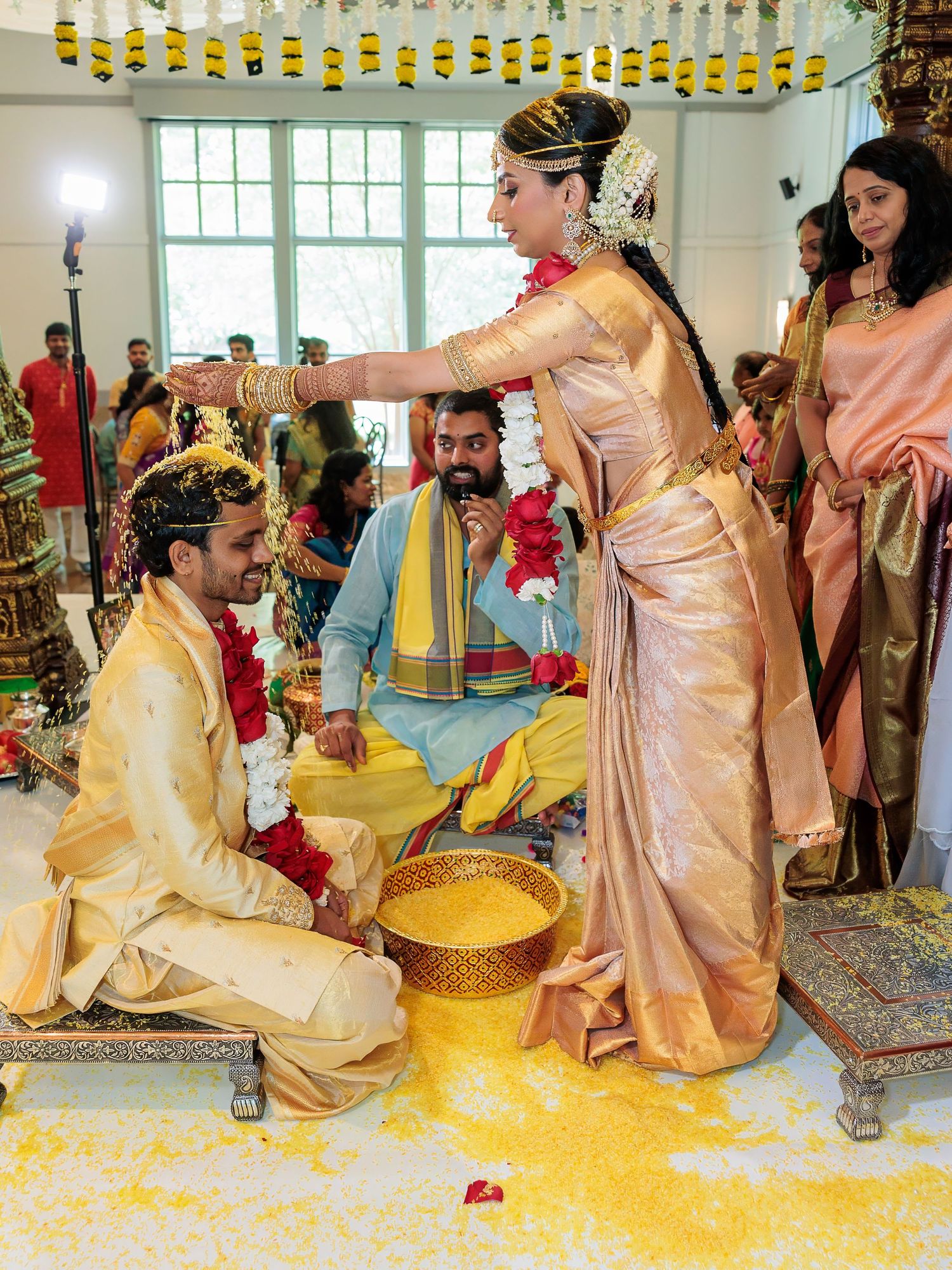 Traditional Indian wedding ceremony showing turmeric ritual with yellow powder and decorative elements.