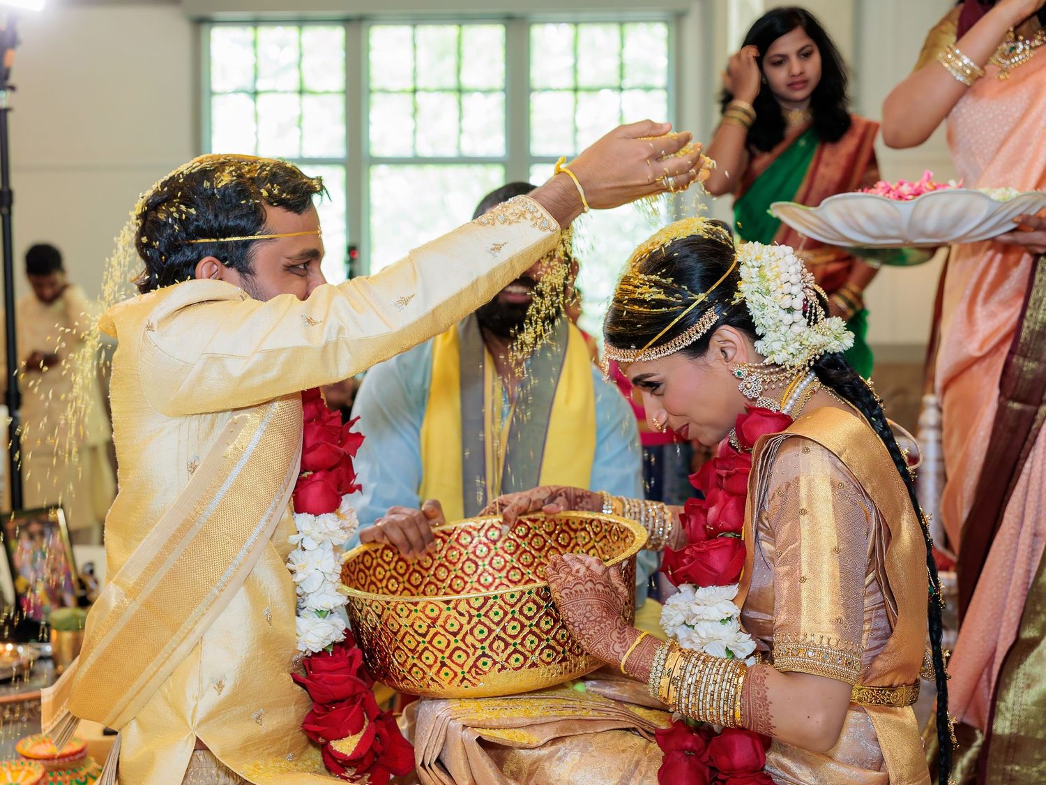 Traditional wedding ceremony with yellow powder and ceremonial items in decorated indoor setting.