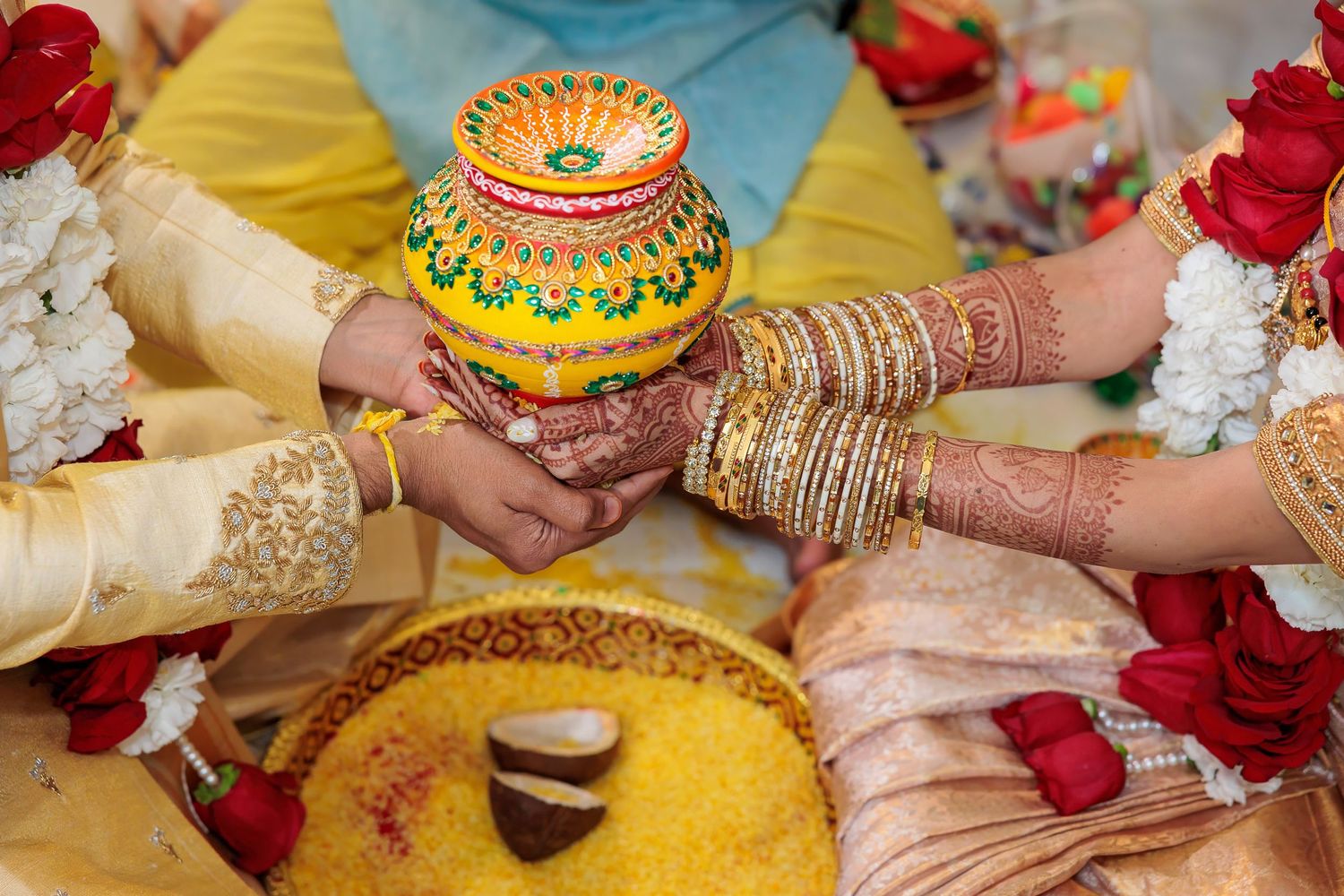 Decorated ceremonial items and jewelry-adorned hands during traditional Indian wedding rituals.