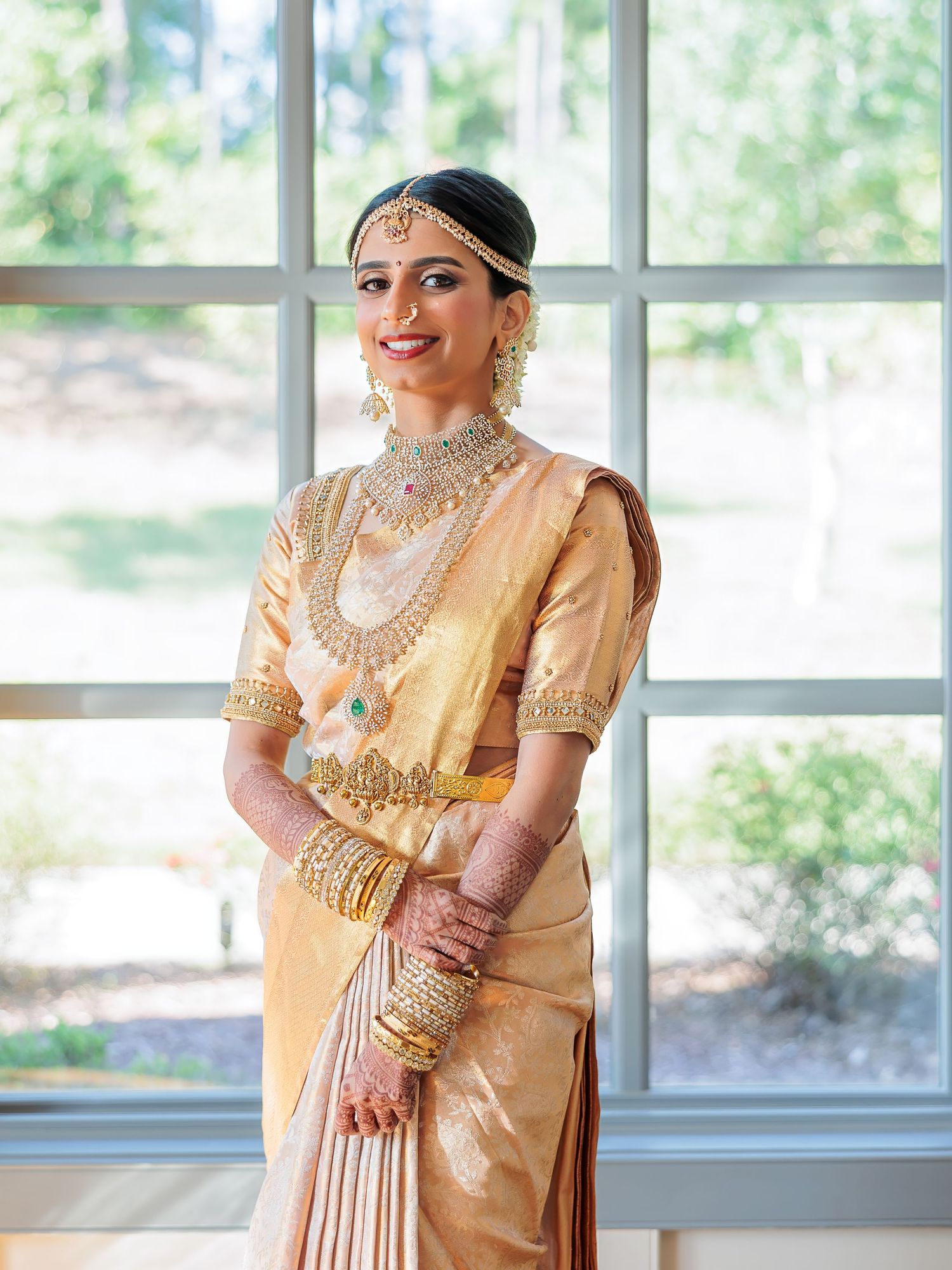 South Indian bride in cream silk saree with intricate gold jewelry and traditional bridal accessories.
