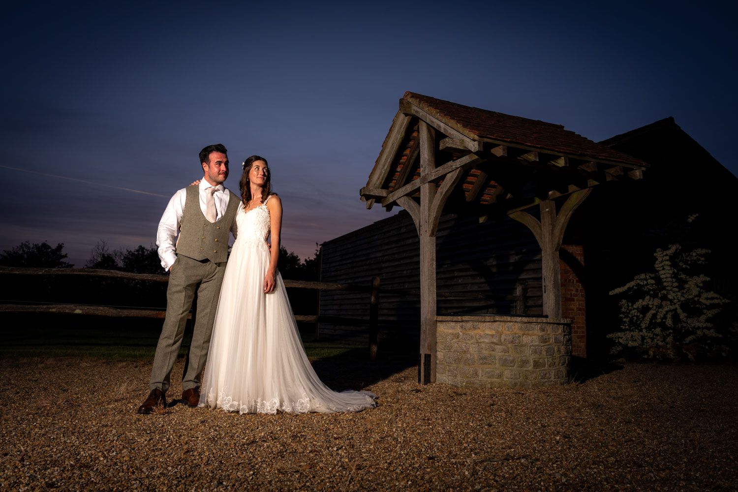 Bride and groom pose at dusk at Clock Barn wedding venue.