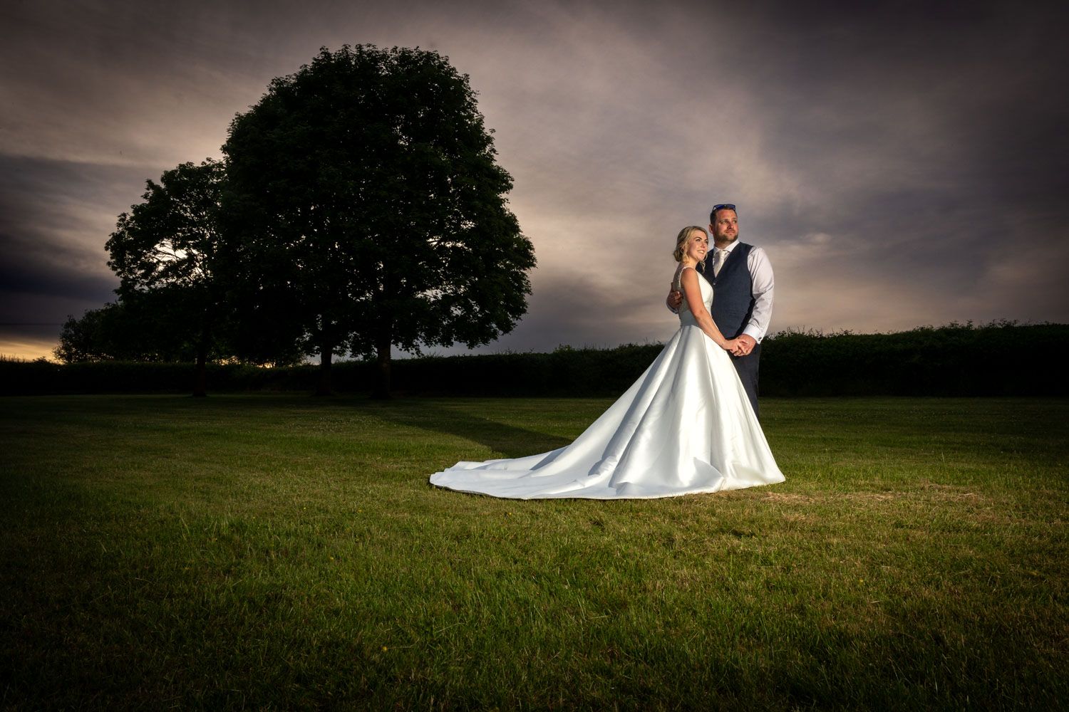 Bride and groom at dusk with dramatic cloudy sky at Pinglestone Barn