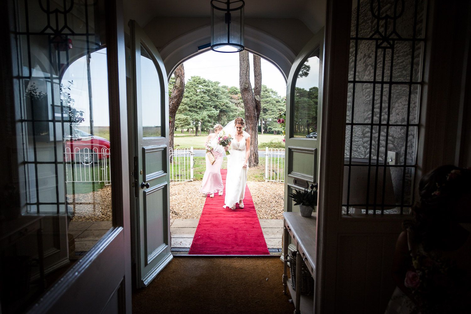 View through elegant arched doorway showing red carpet path leading outside to garden and terrace.
