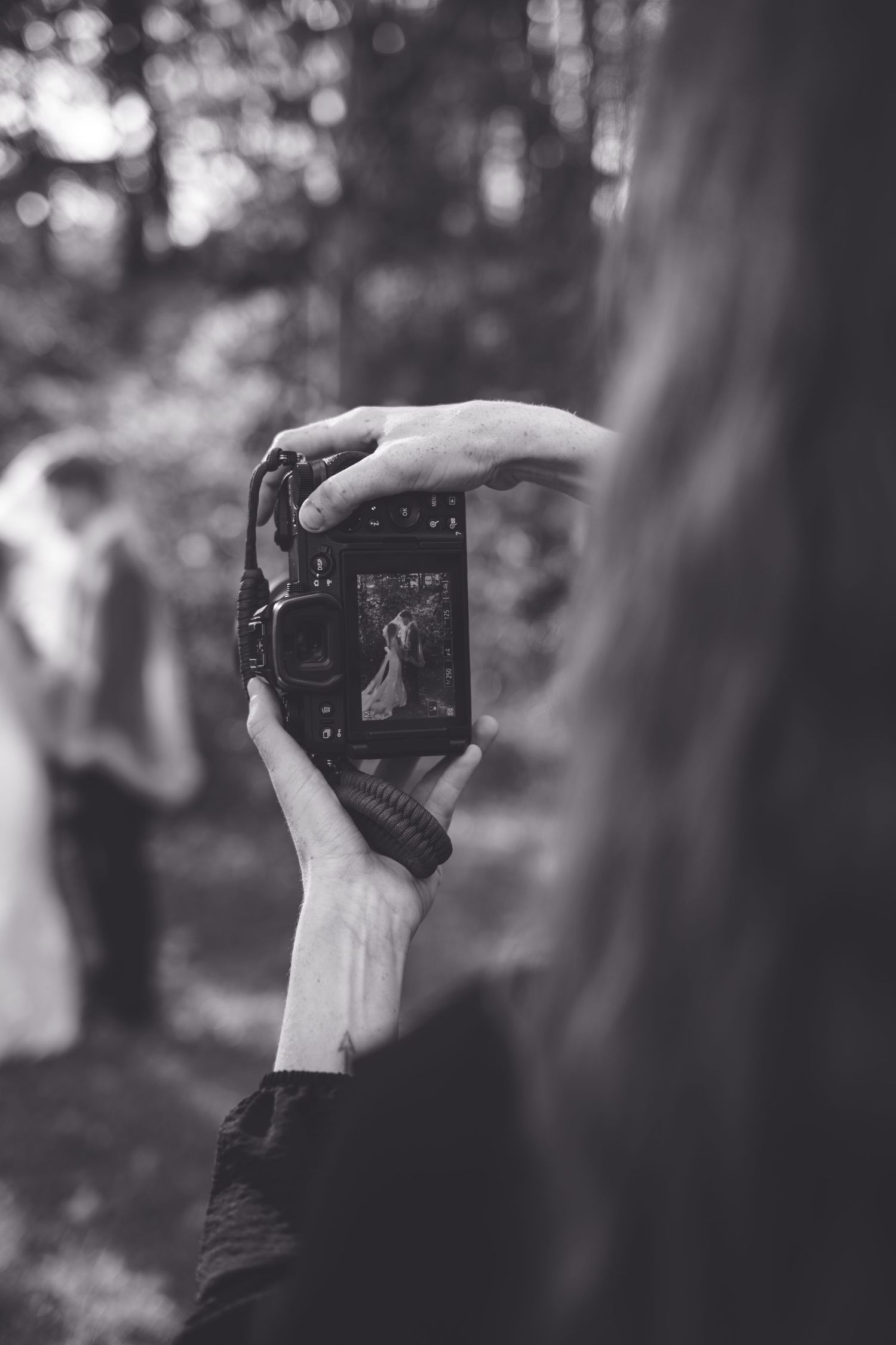 A series of black and white photos showing hands holding a camera in different positions against a blurred background.