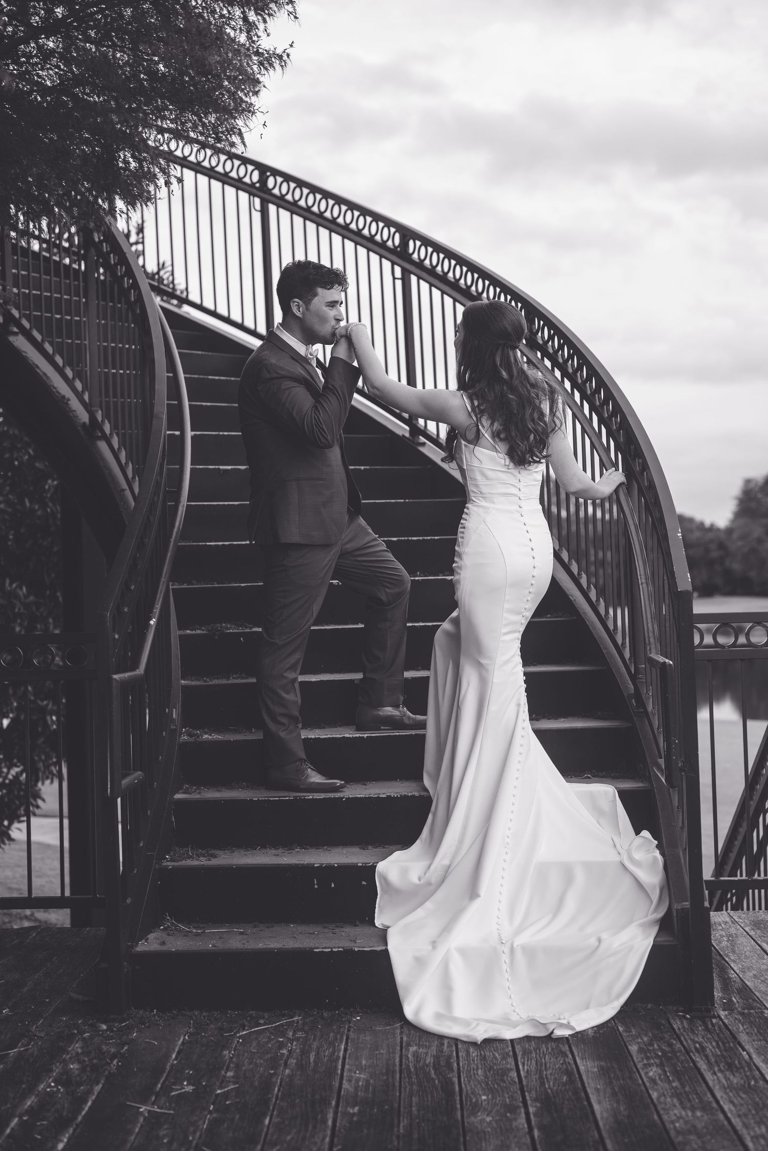 Black and white photo of newlyweds posing on decorative metal stairs outdoors. River landing, Wallace, NC