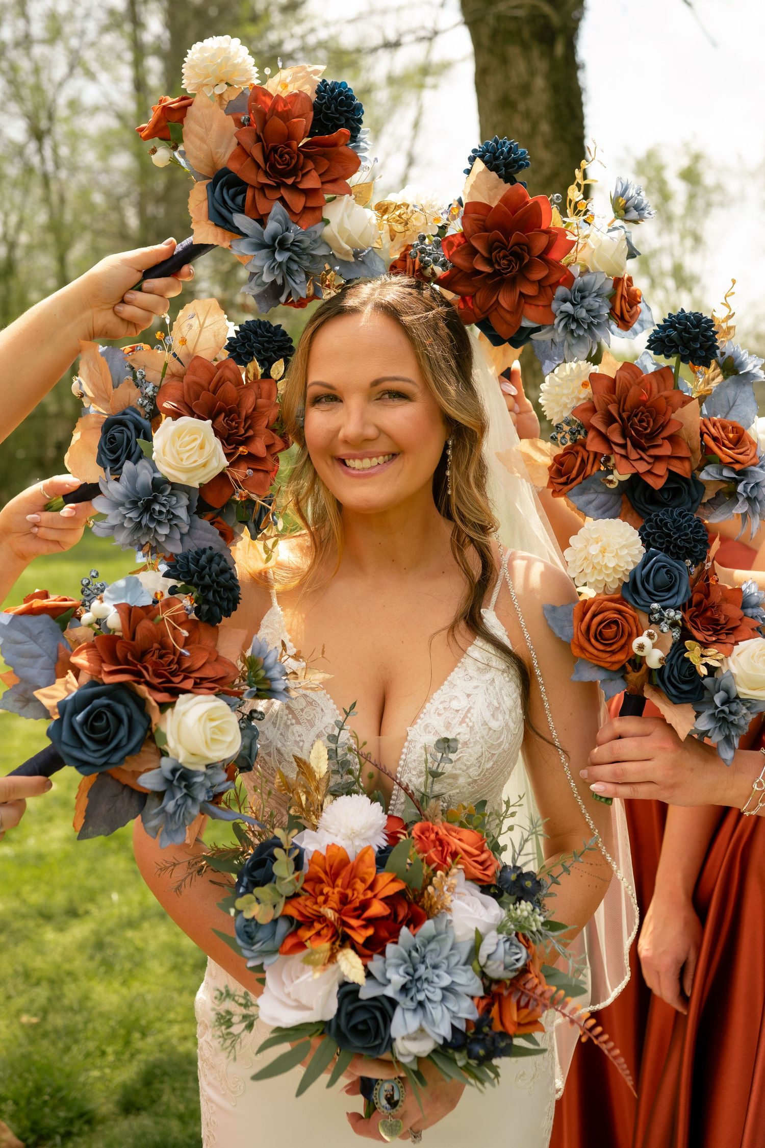 Bride smiles through a floral wreath of rust, navy, and ivory blooms while holding a matching bouquet.