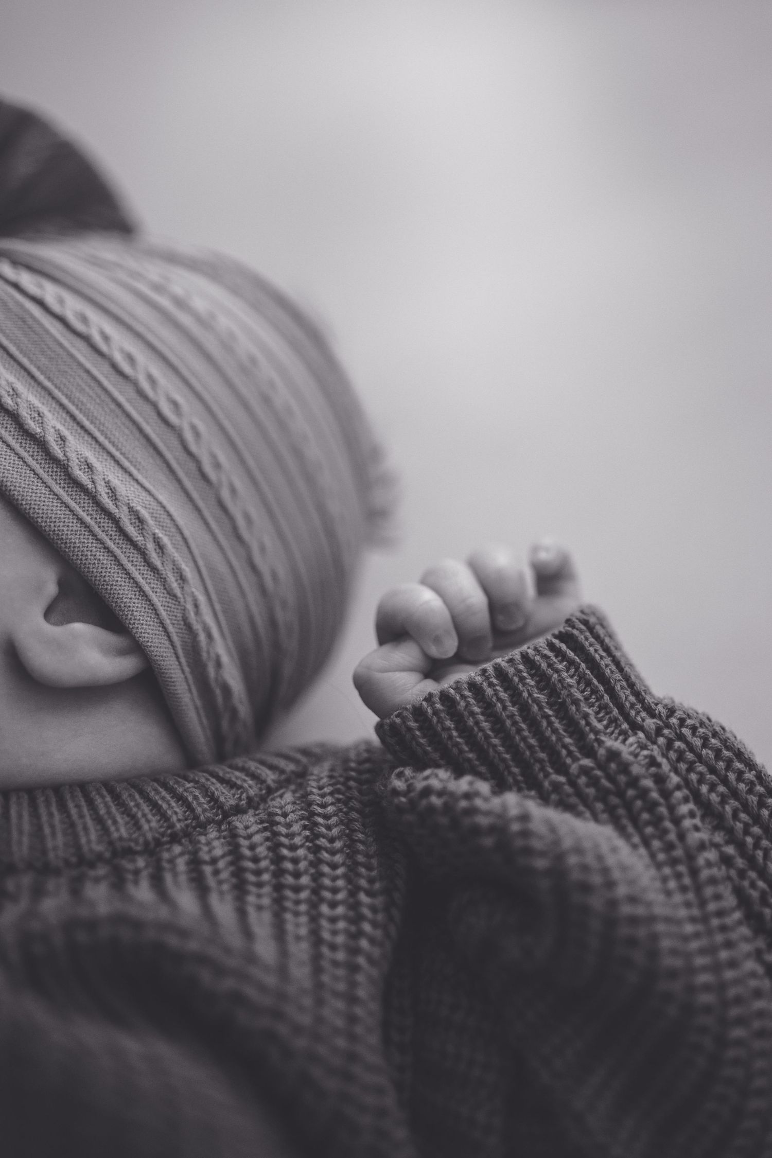Black and white close-up image showing someone wearing a cozy knit sweater while resting. Southern Pines, NC