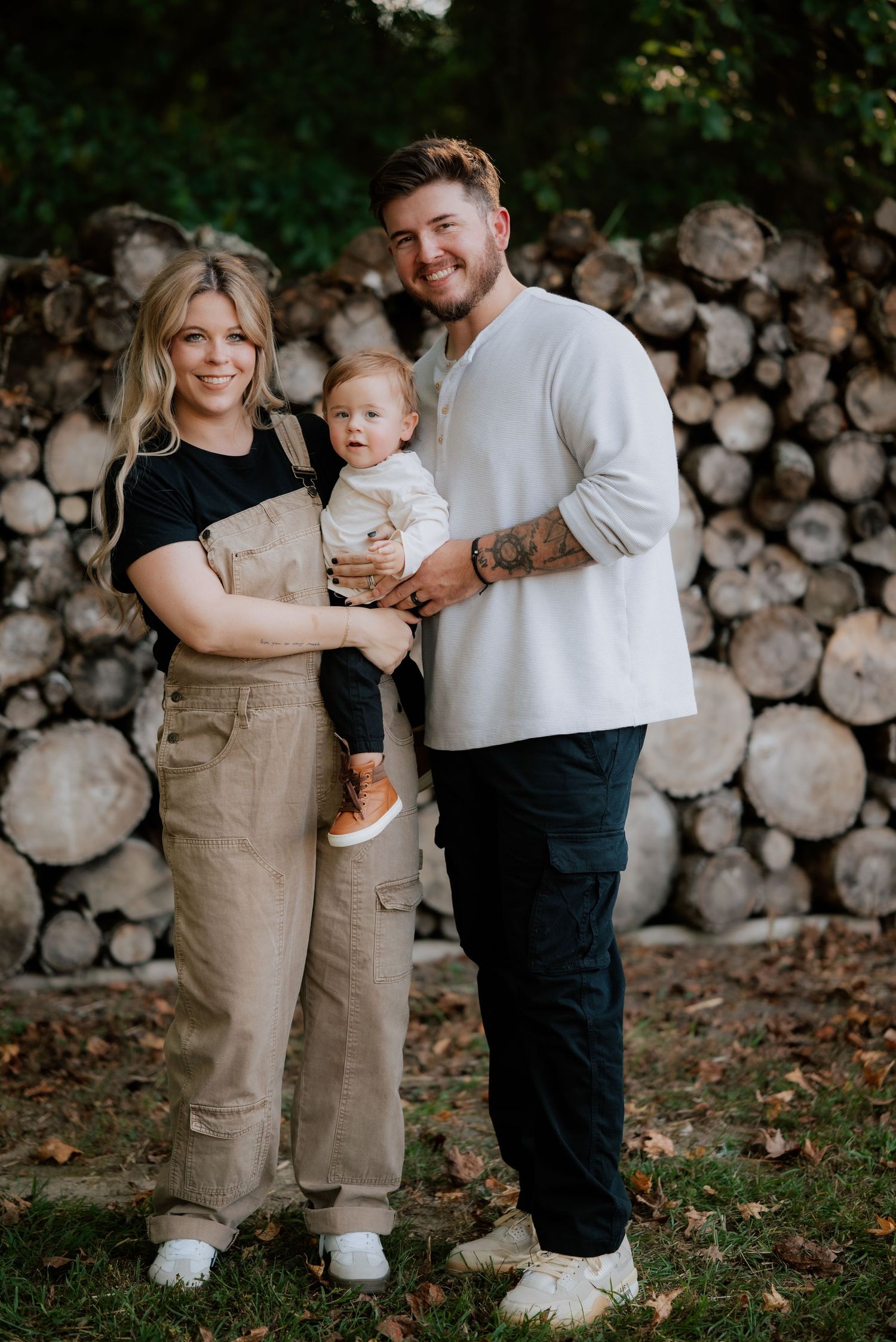 Family portrait against rustic wood pile backdrop in casual attire. North Carolina