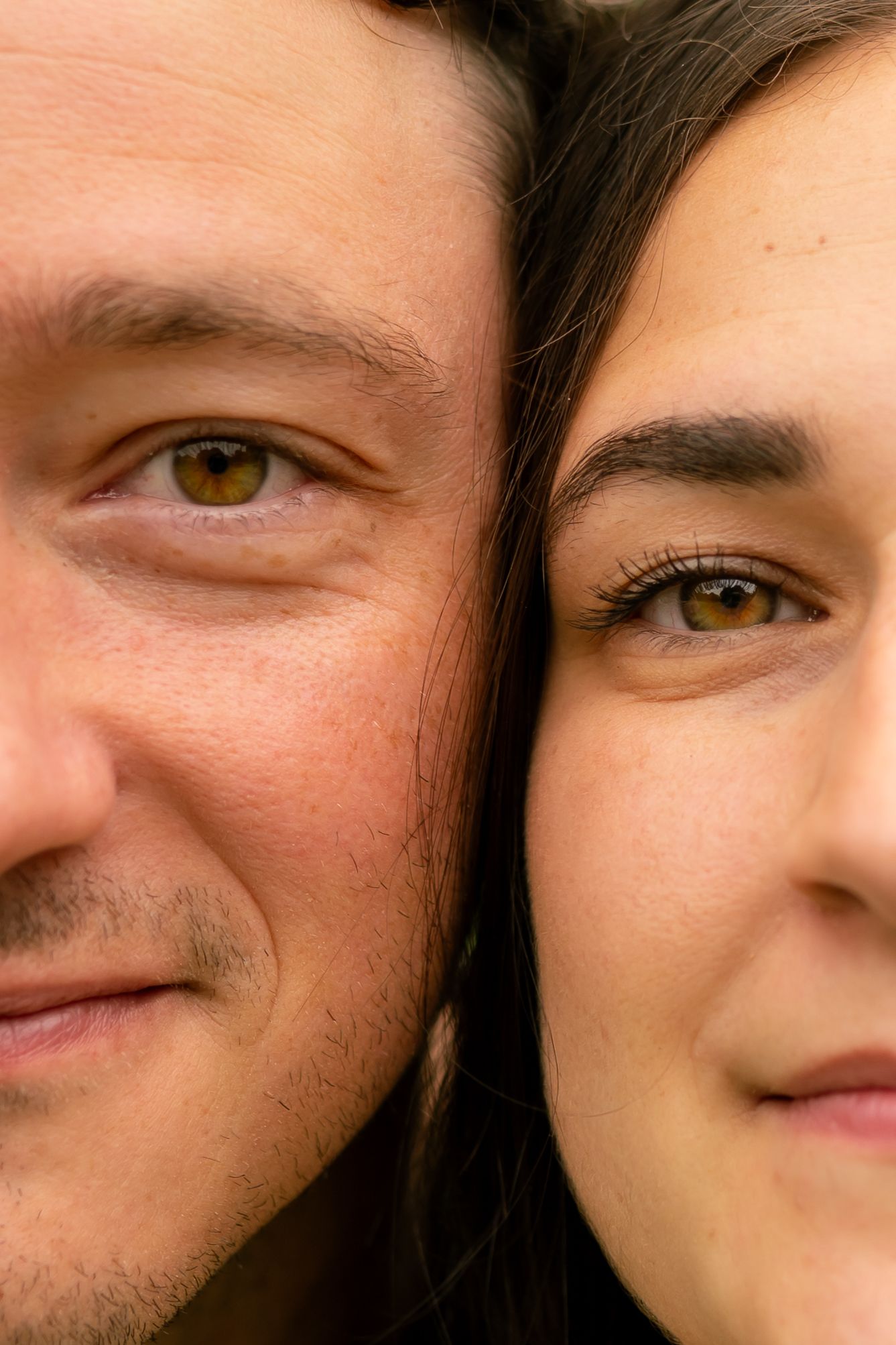 Close-up portrait of a man and woman side by side, both with hazel eyes and dark hair, smiling warmly.