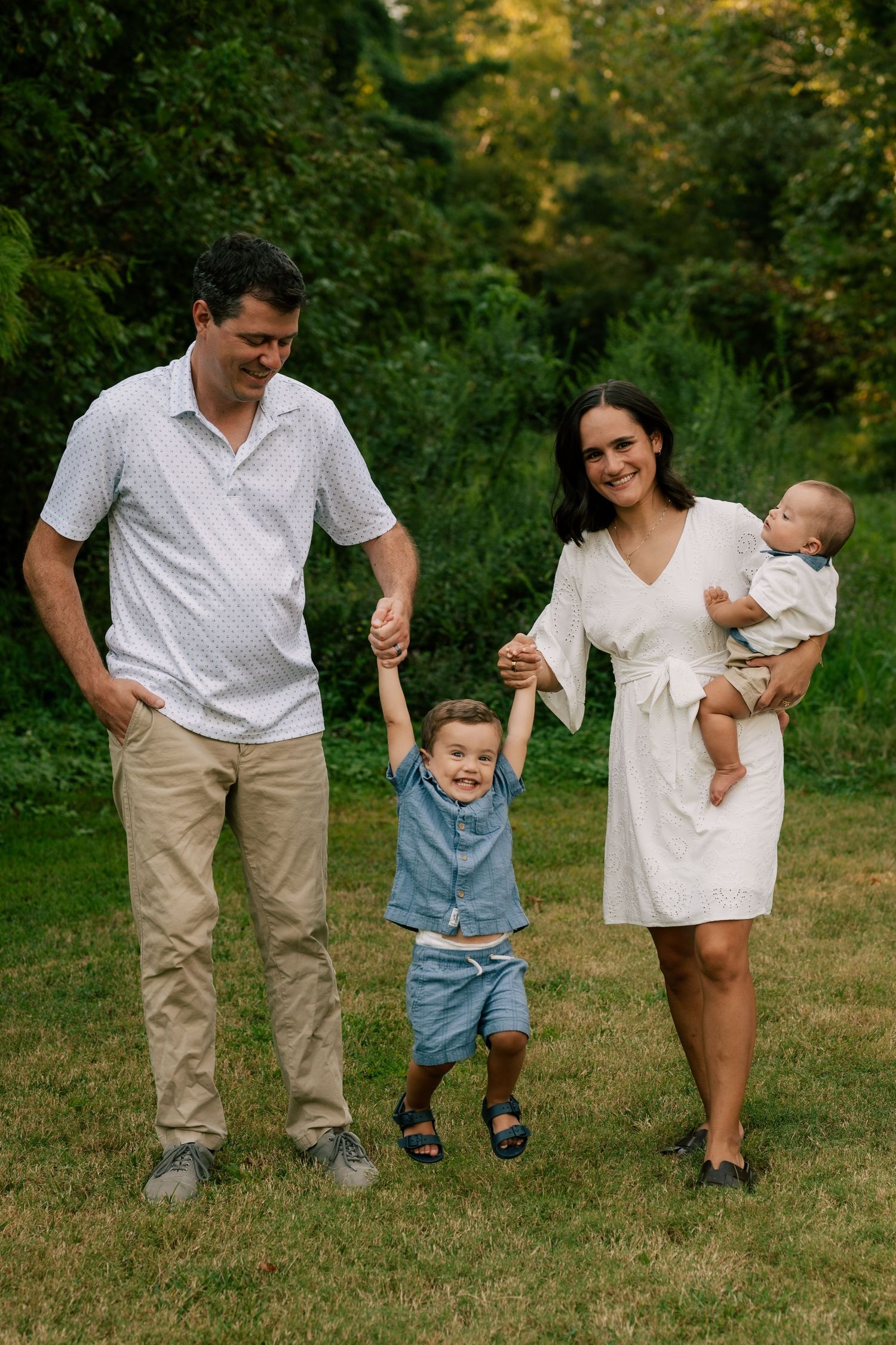 A series of candid family photos showing parents walking with children on grass in a natural outdoor setting.