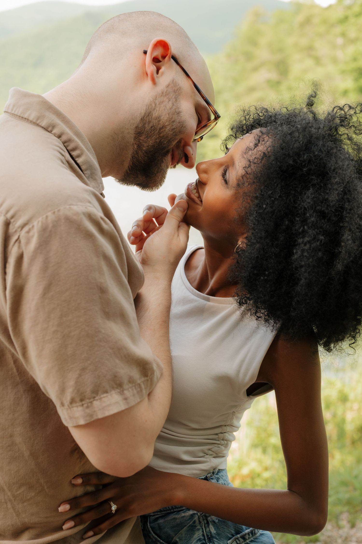 Intimate couple sharing a tender moment outdoors against a natural sunlit backdrop. in North Carolina