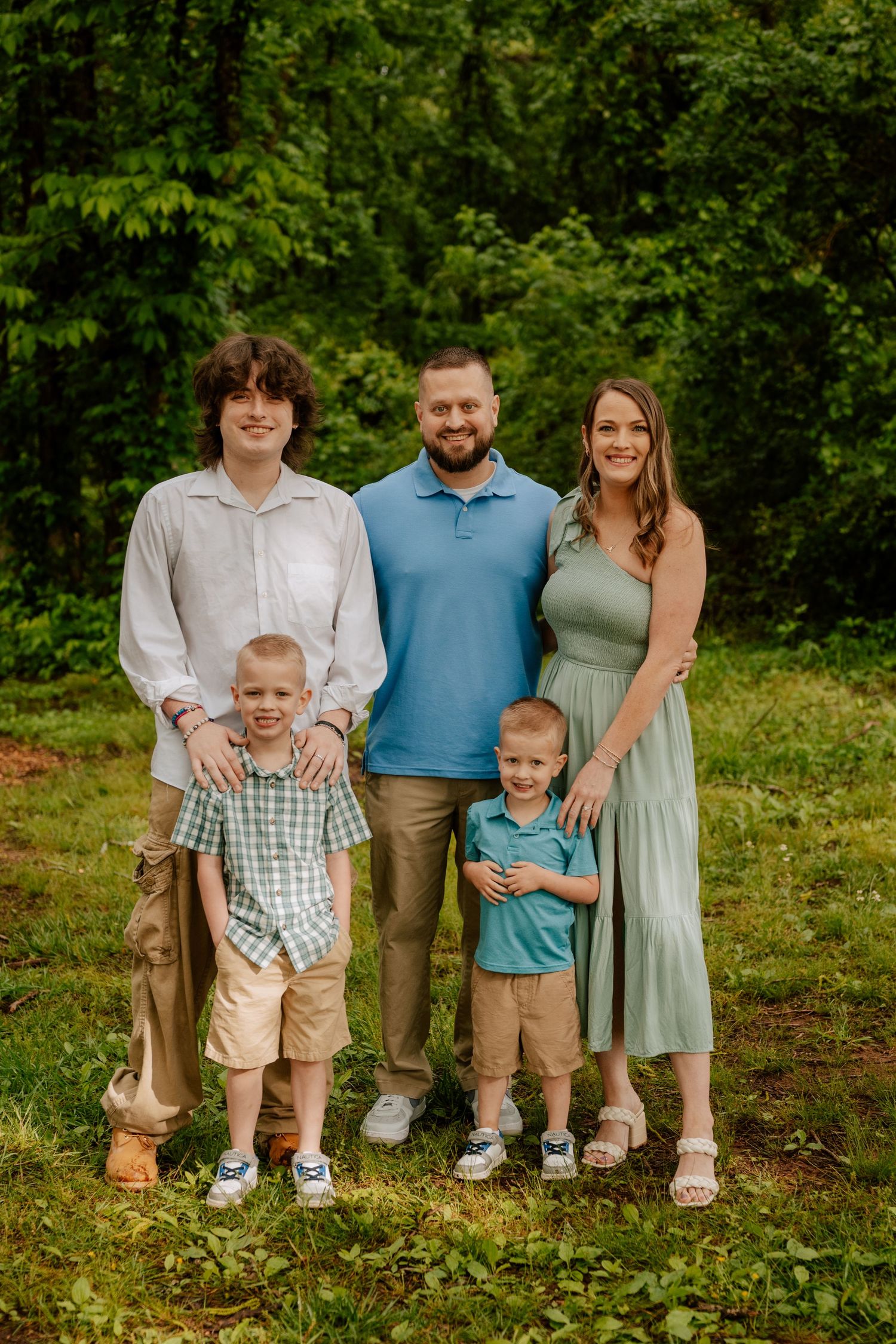 A series of cropped family portraits showing legs and feet arranged in a row against a lush green outdoor backdrop.