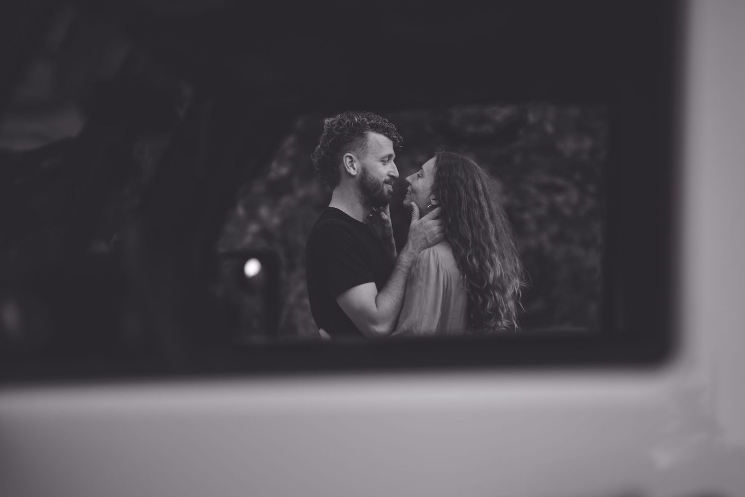 An intimate black and white portrait of a couple in a loving embrace.