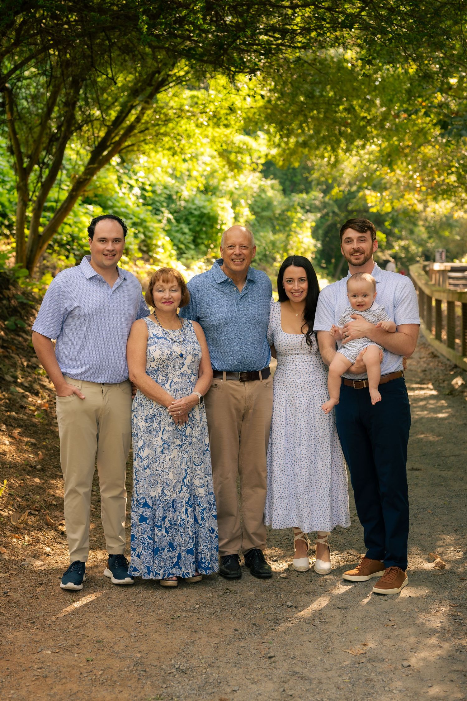 A group of people wearing coordinated blue and white outfits pose together outdoors on a sunny day.