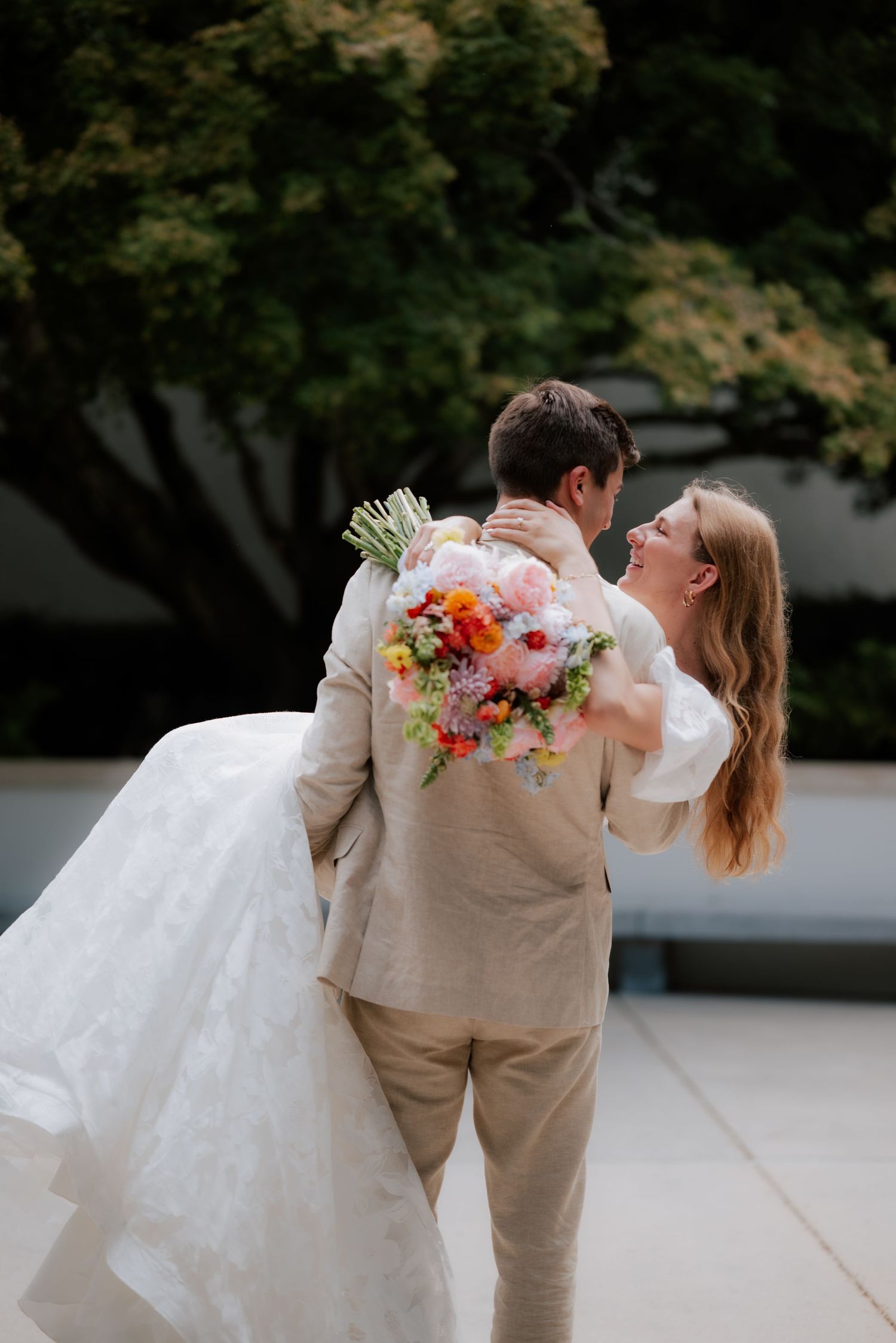 Romantic wedding portrait showing a couple dancing with vibrant floral bouquet.