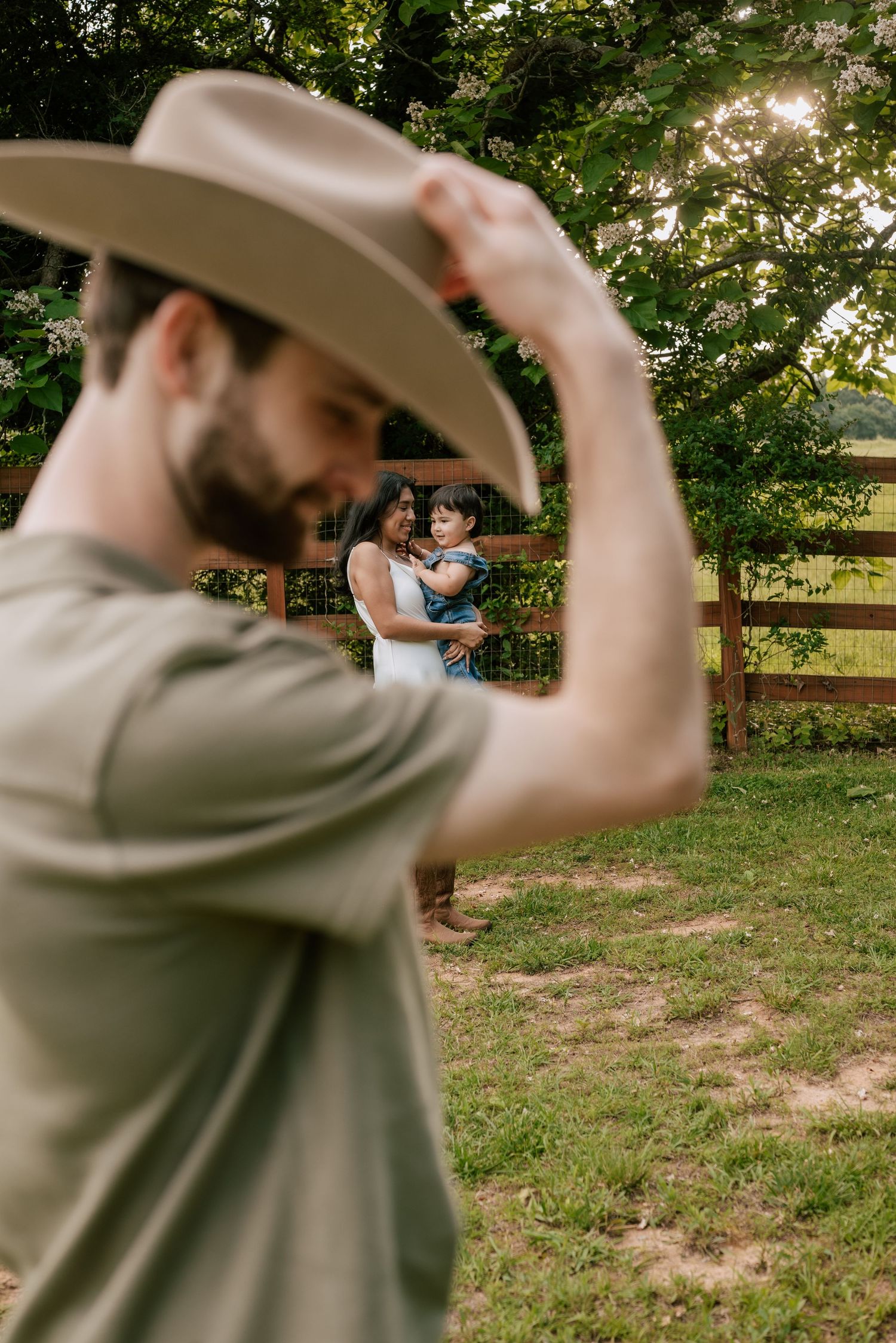 A series of progressive shots showing someone adjusting their cowboy hat in a grassy outdoor setting with wooden fencing.