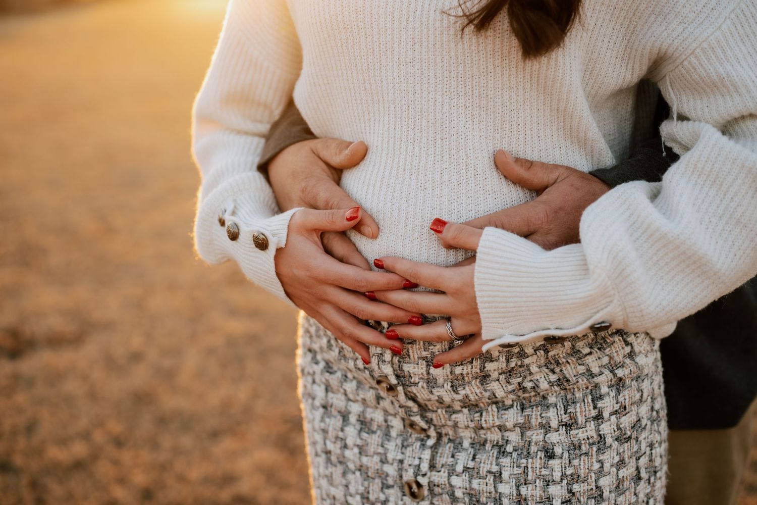 A couple embraces in a romantic moment wearing white and floral outfits during golden hour.