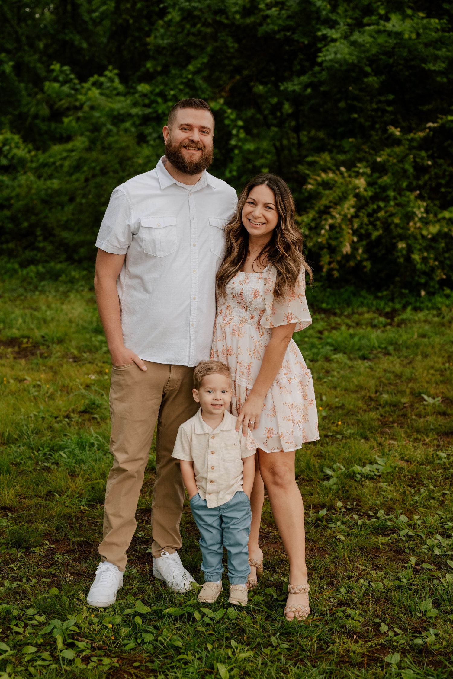 Family posing together outdoors in coordinated outfits on grassy area with trees in background. In North Georgia ; True to color