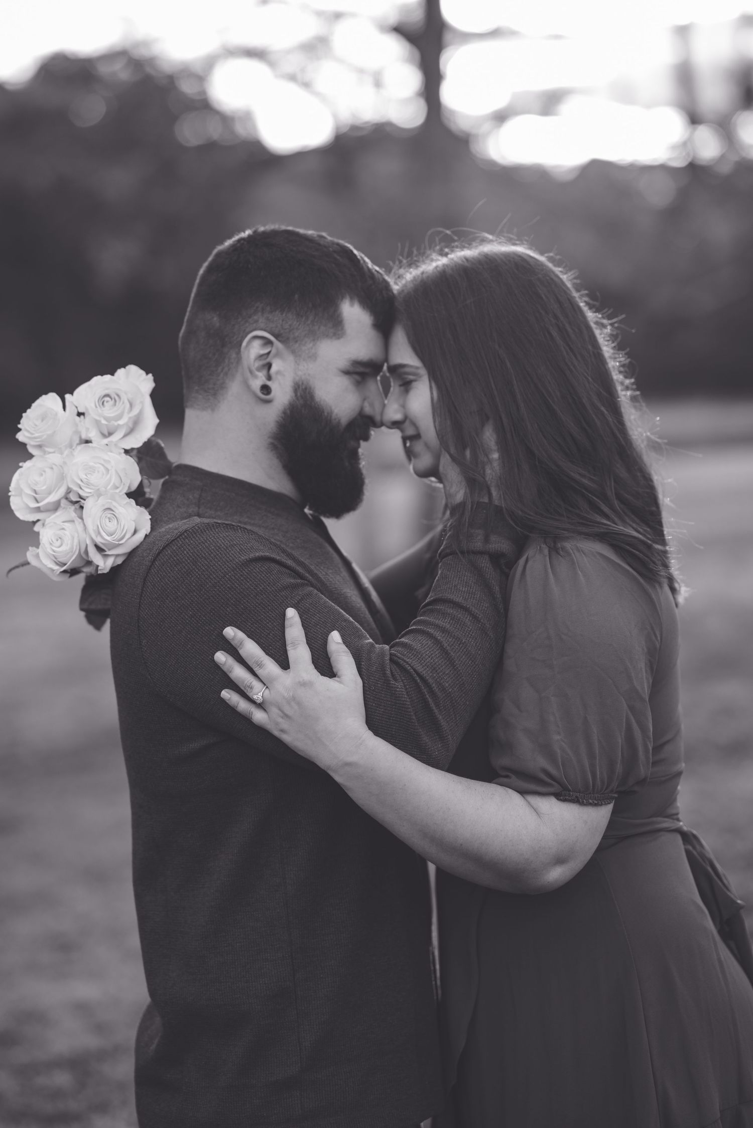 Intimate black and white portrait of couple embracing with white roses.