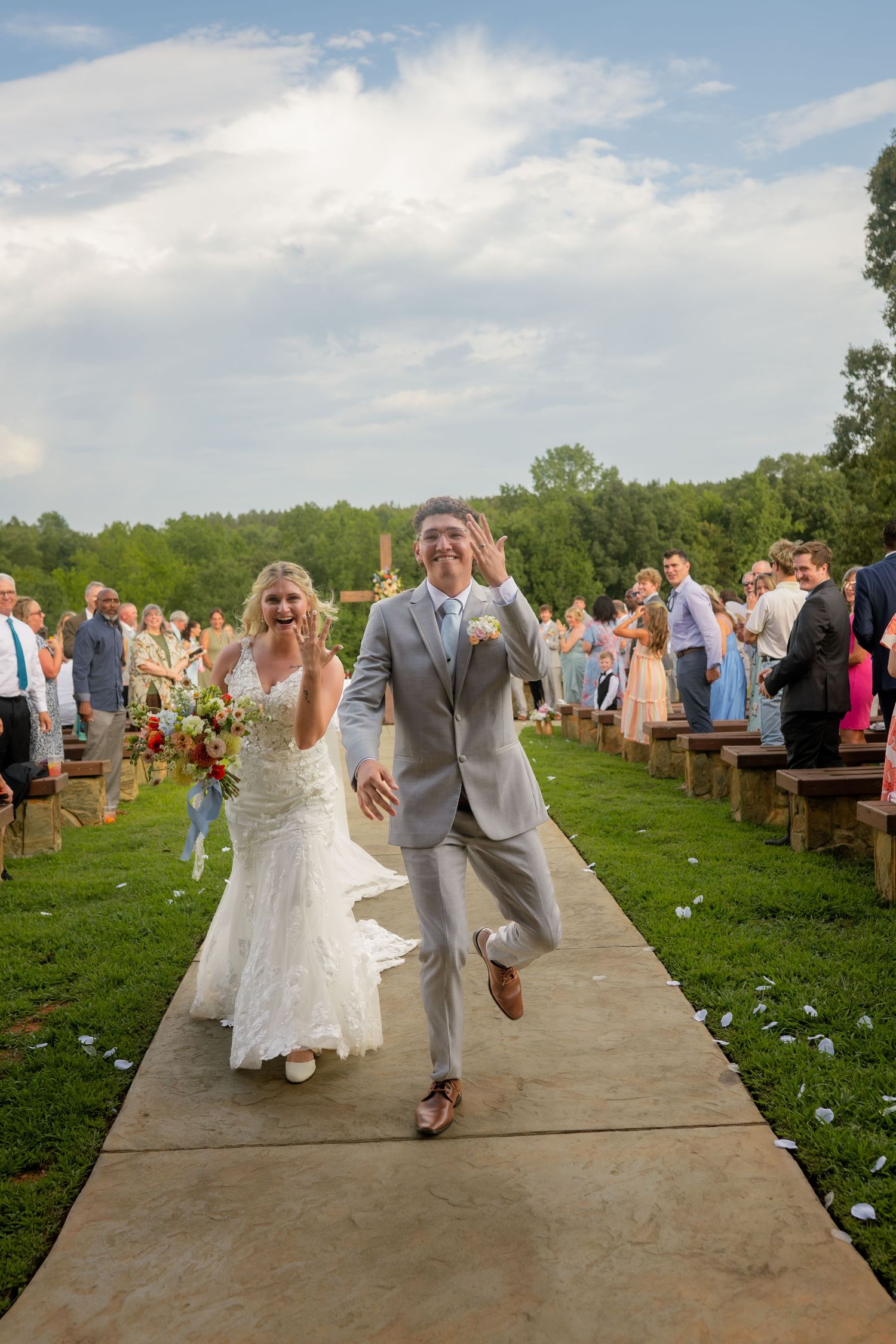 Joyful bride and groom celebrating as they walk down the aisle at their outdoor wedding ceremony.