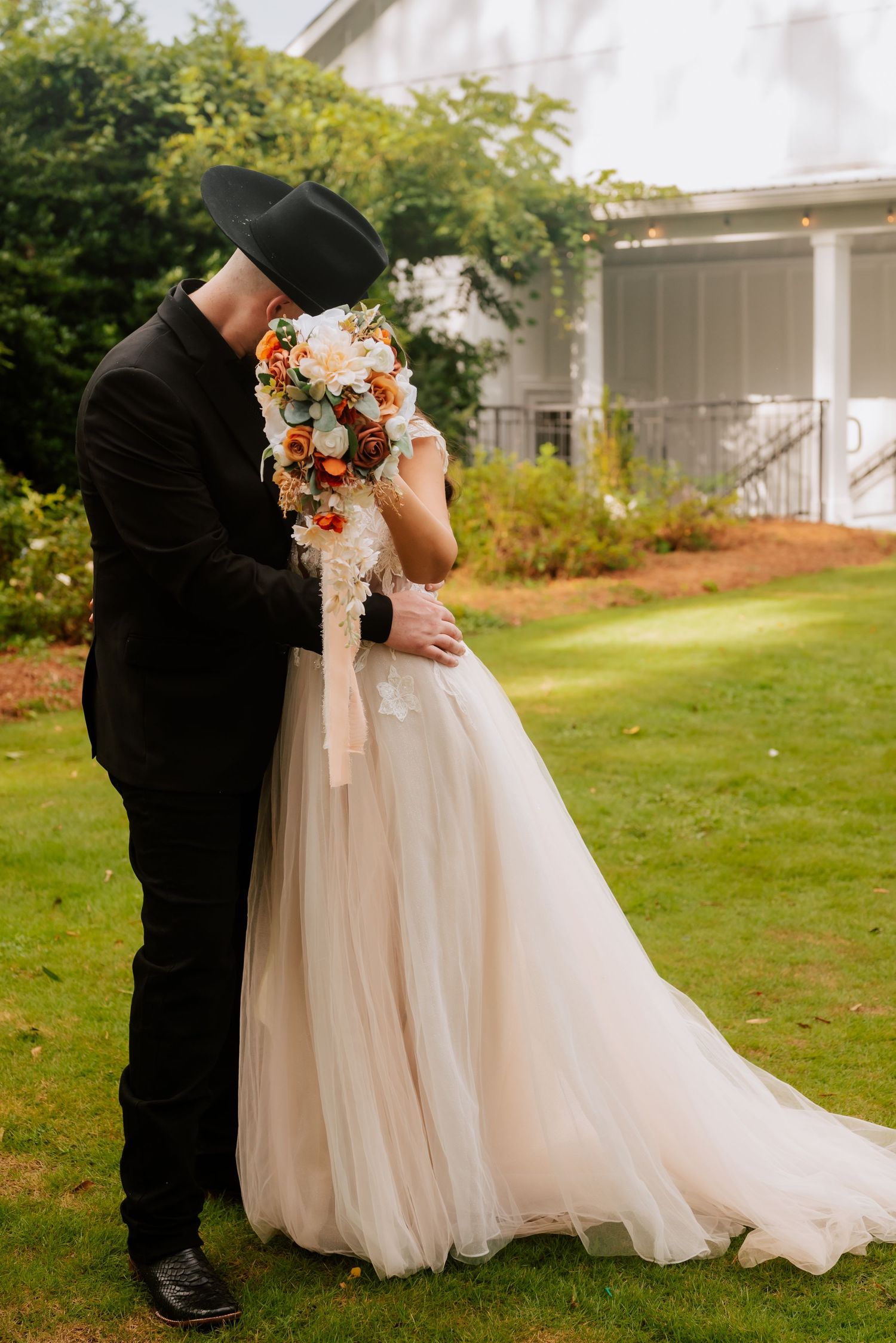 Bride and groom hiding a kiss behind wedding bouquet.