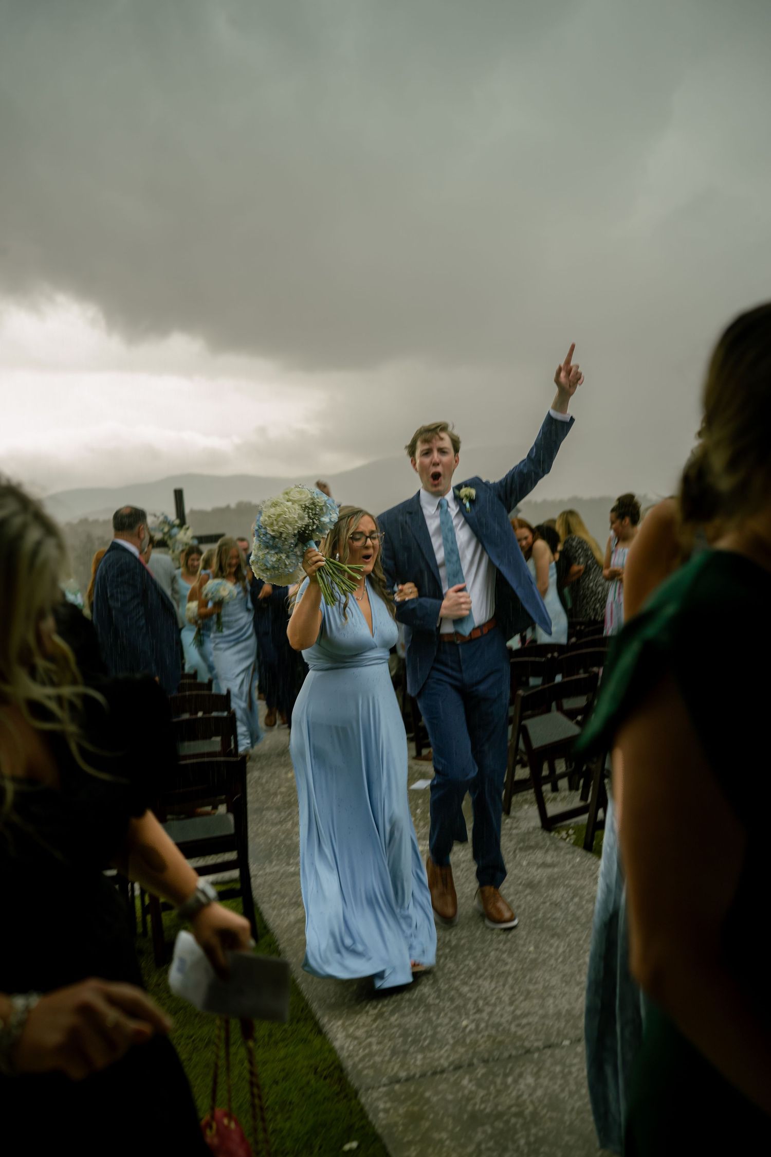 Bridesmaid in blue gown and groomsman celebrating joyfully after outdoor wedding ceremony.
