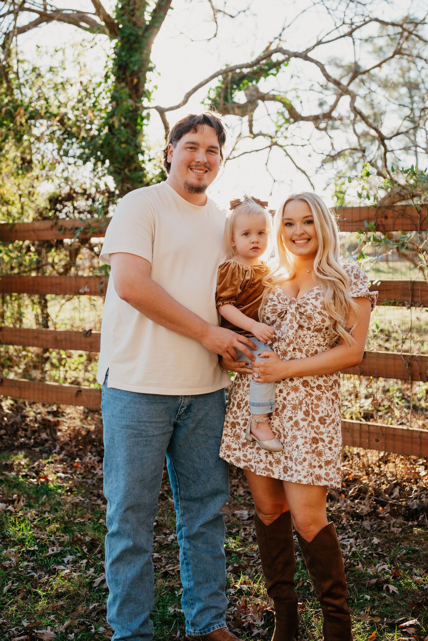A family poses together for an autumn portrait in front of a wooden fence.