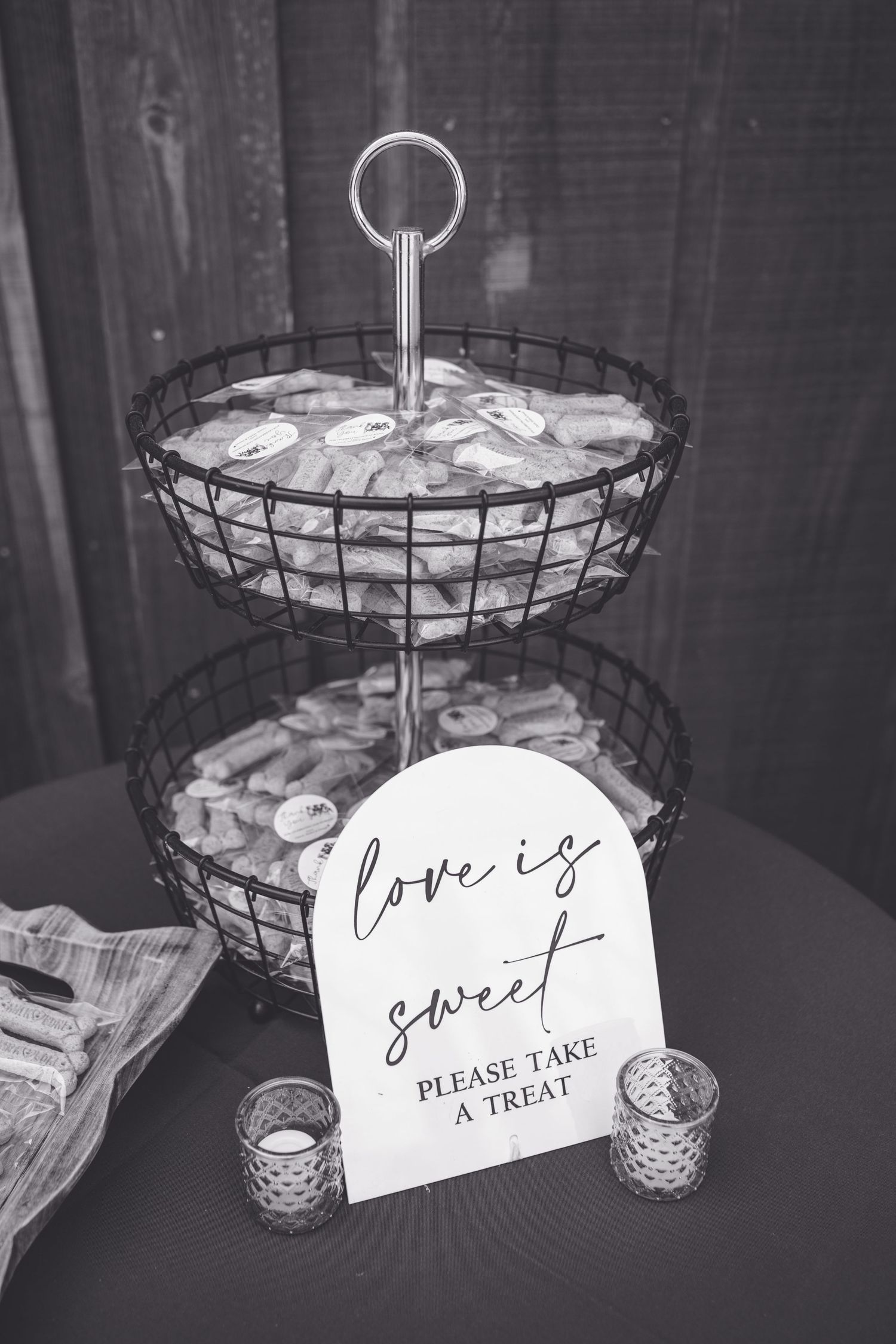 Black and white wedding candy bar with tiered wire basket and love is sweet please take a treat sign.