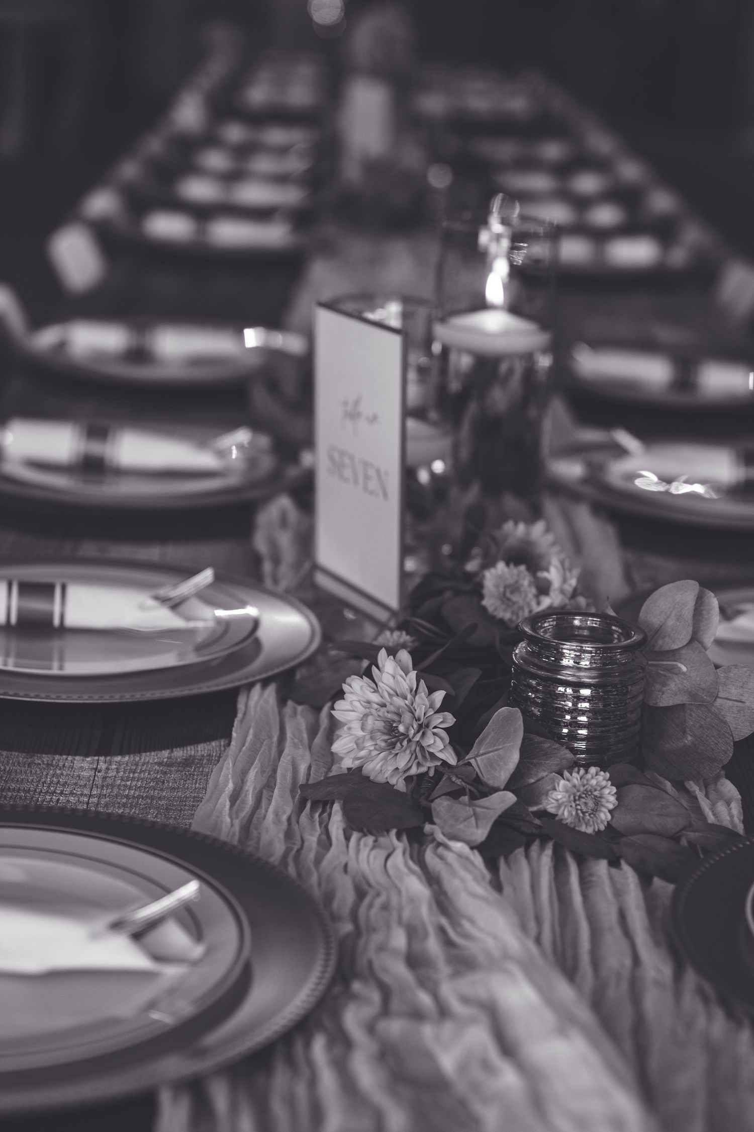 Elegant table setting with black plates and floral decorations in a moody, dark atmosphere at a formal dinner event.