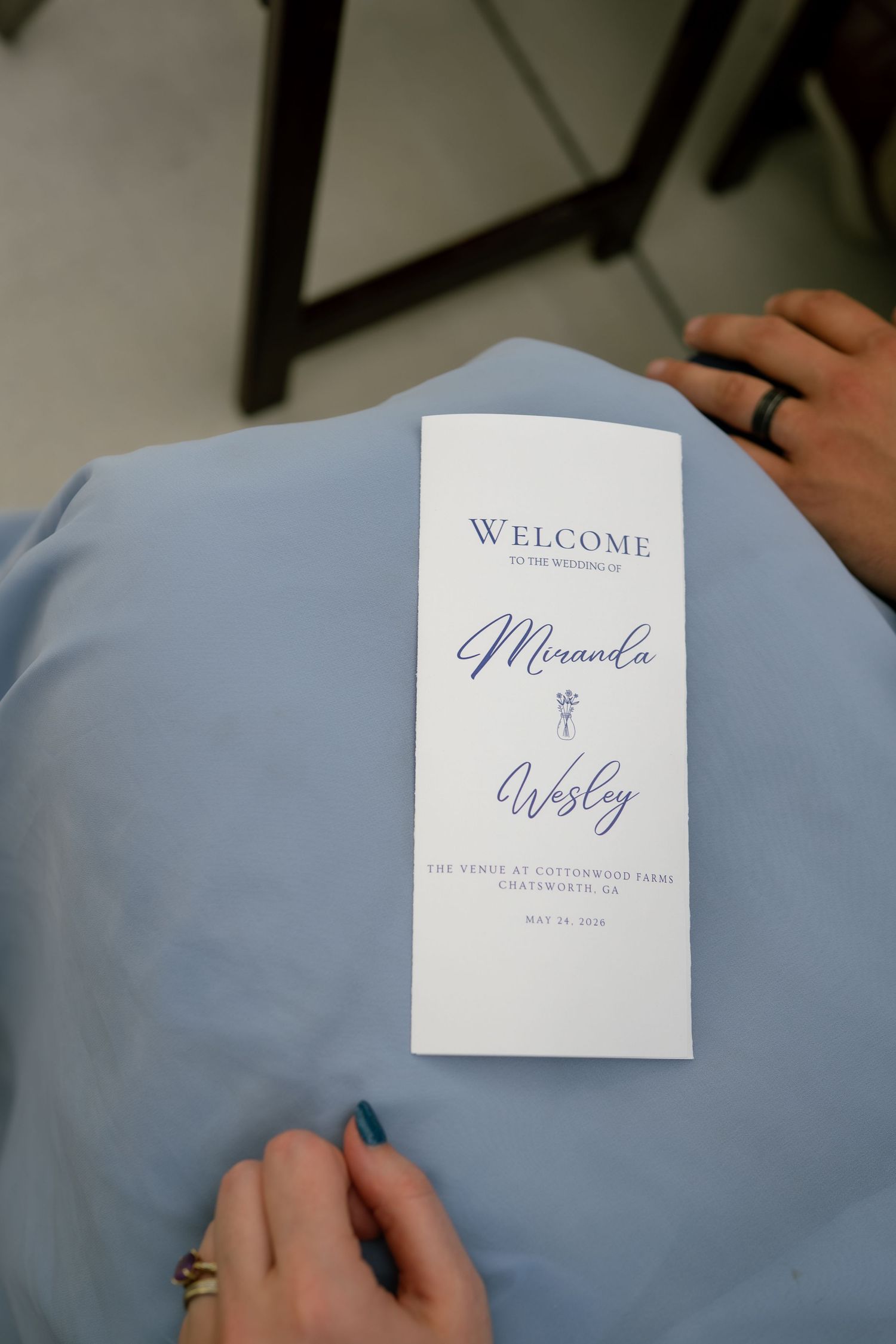 Wedding program for Miranda and Wesley at Cottonwood Farm, Chatsworth, CA, held by a guest in a blue dress.