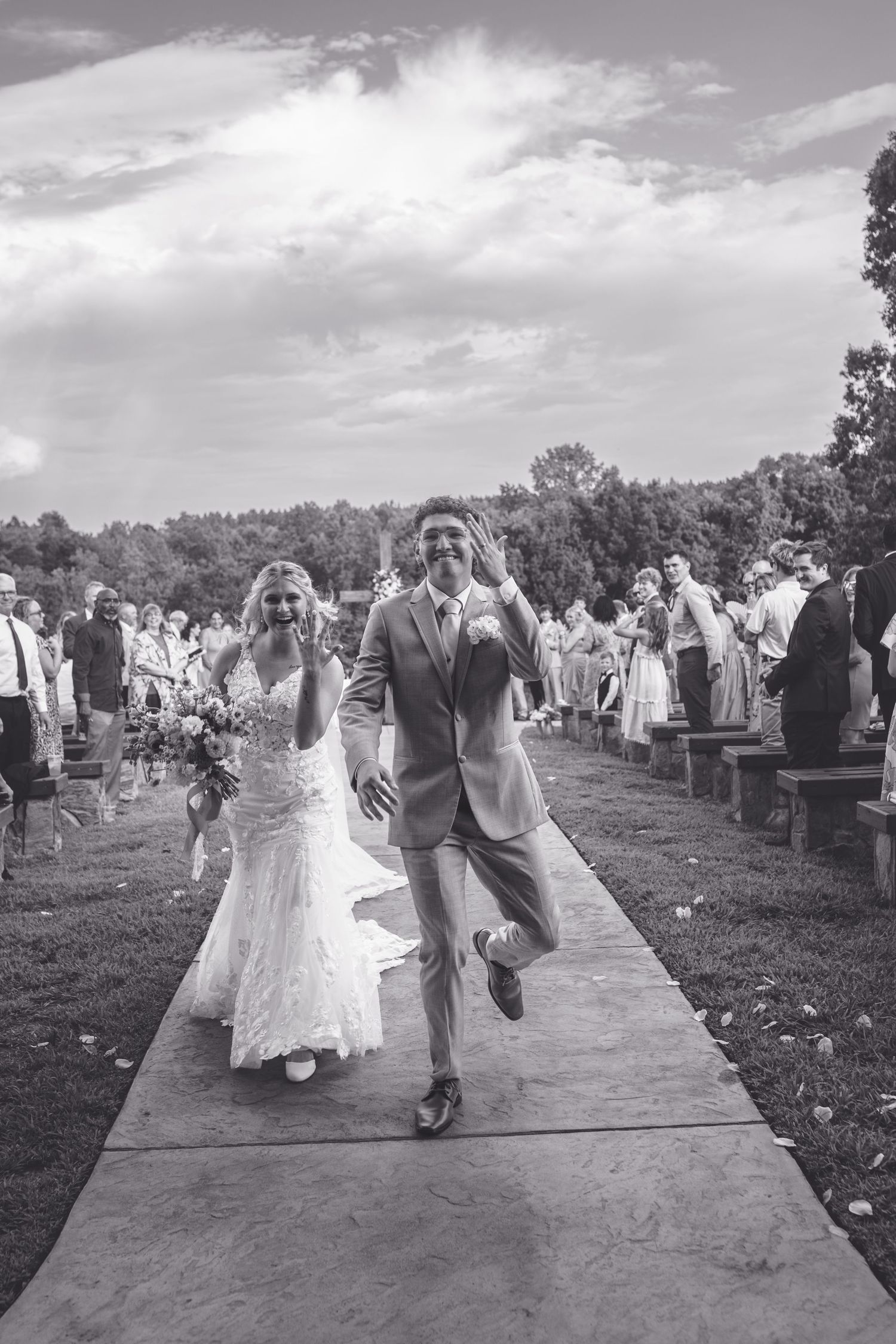 Joyful bride and groom walking back down aisle after outdoor wedding ceremony.