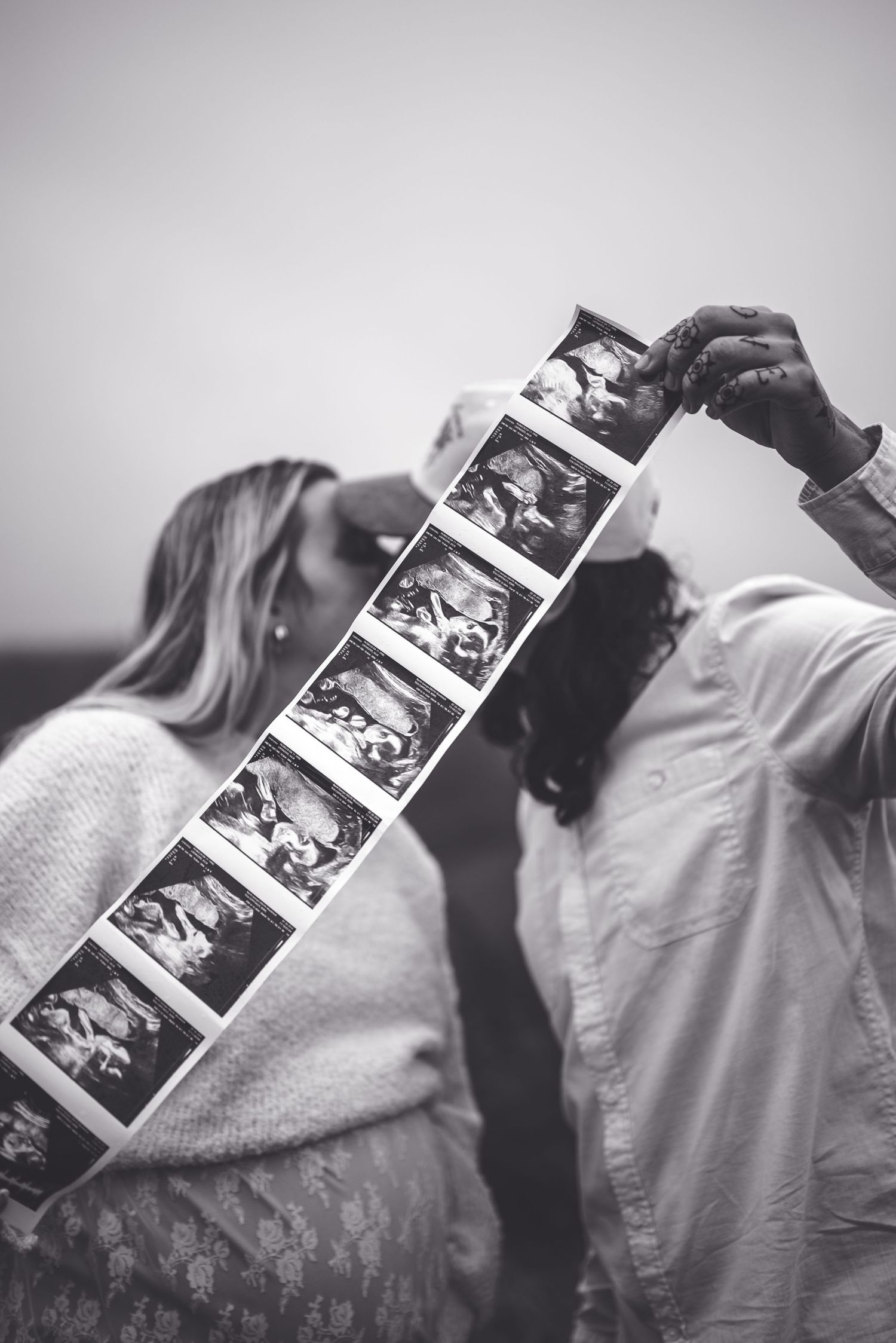 Black and white photo of couple examining ultrasound photos together.