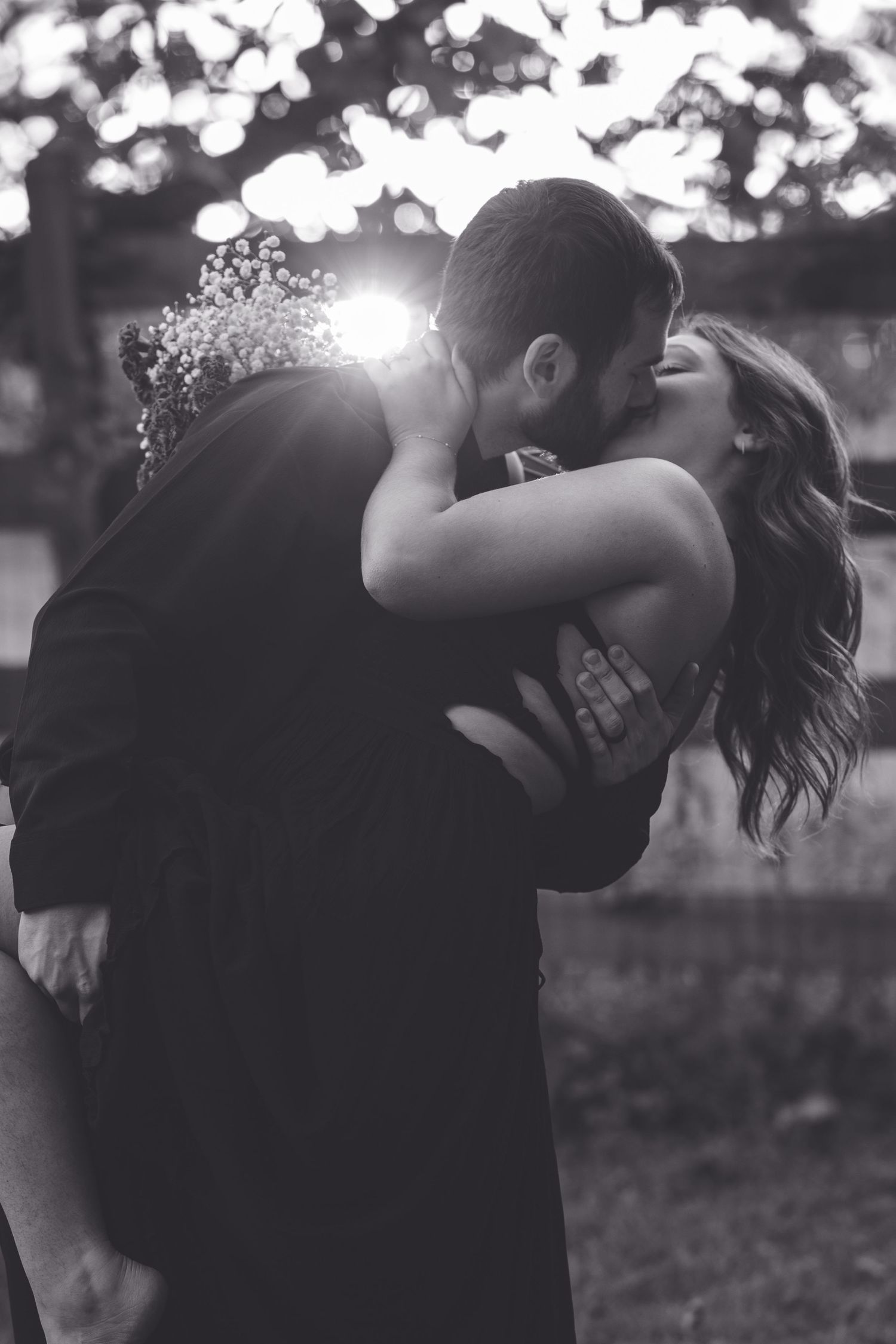 A romantic black and white embrace captured during a wedding celebration outdoors.