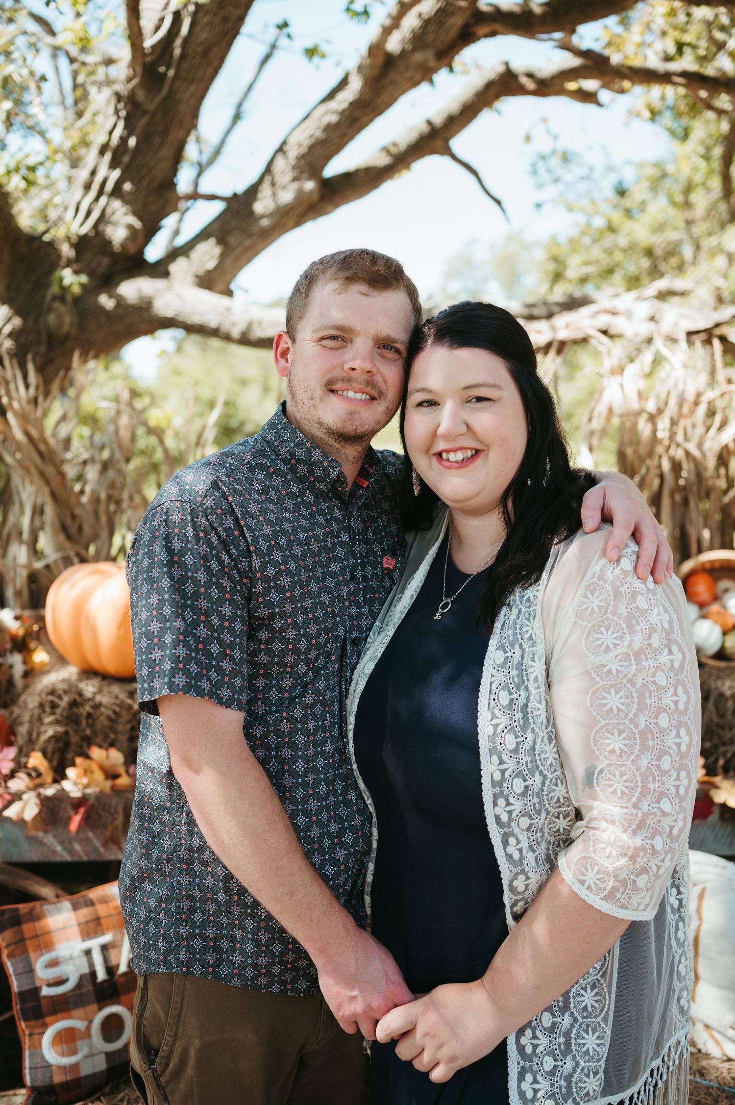 A husband and wife smile and embrace each other during a fall photography session