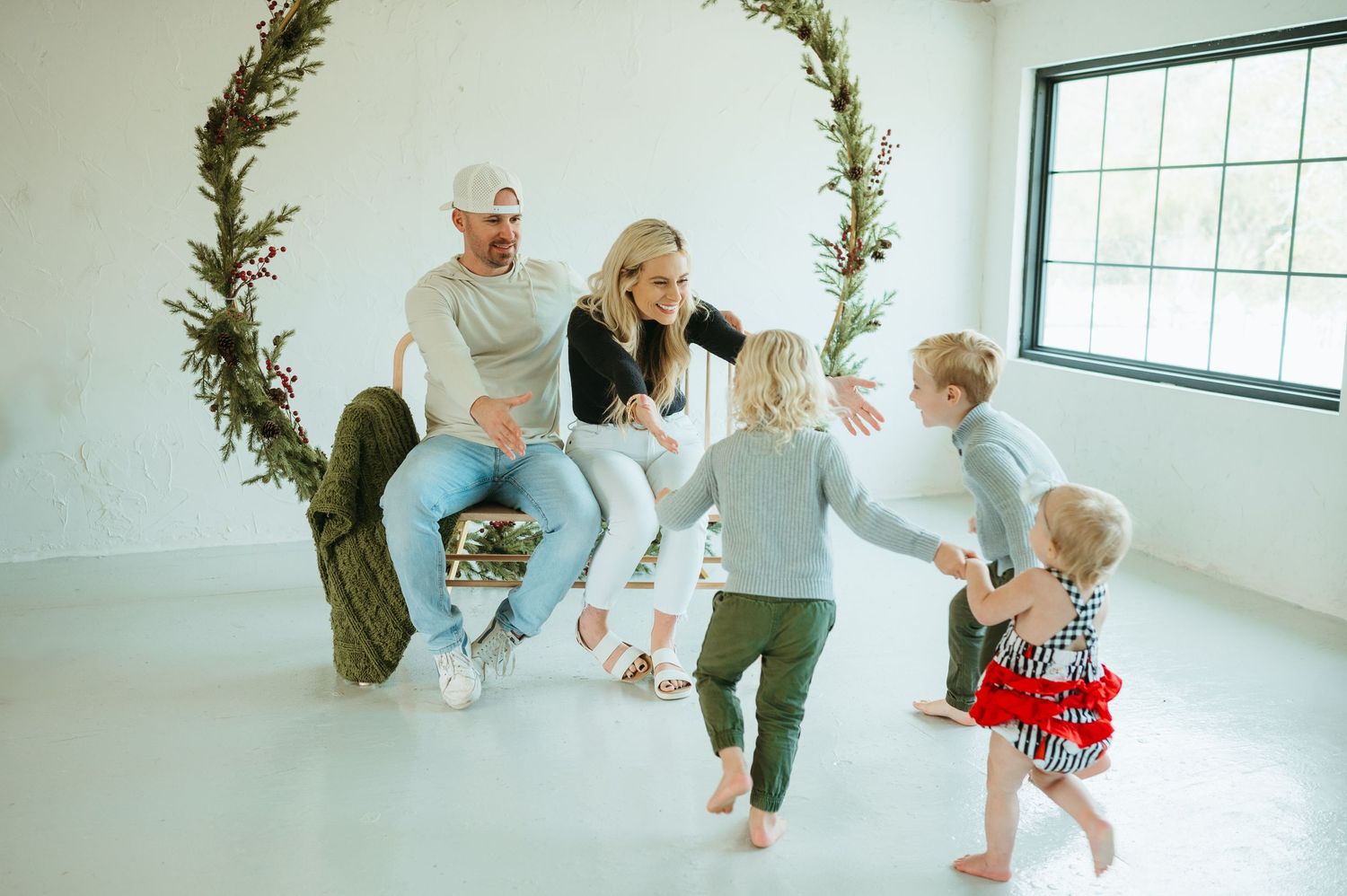 A mother and father reach for their children running to them during a Christmas studio session