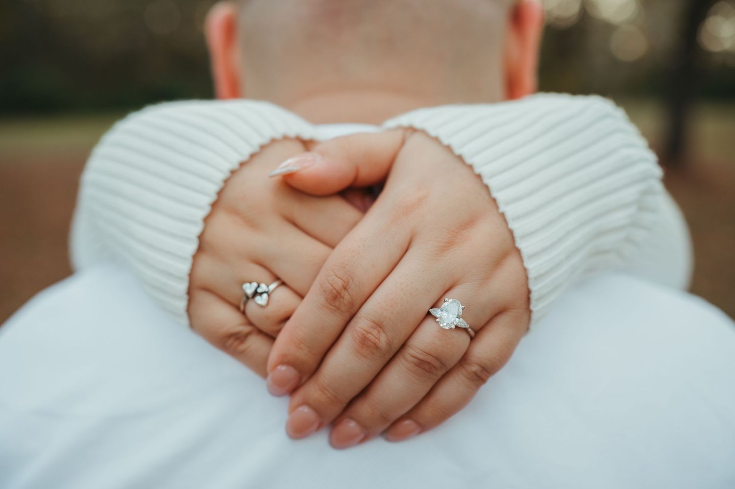 A detail shot of a newly engaged woman's hands around her fiancés neck to show off her ring