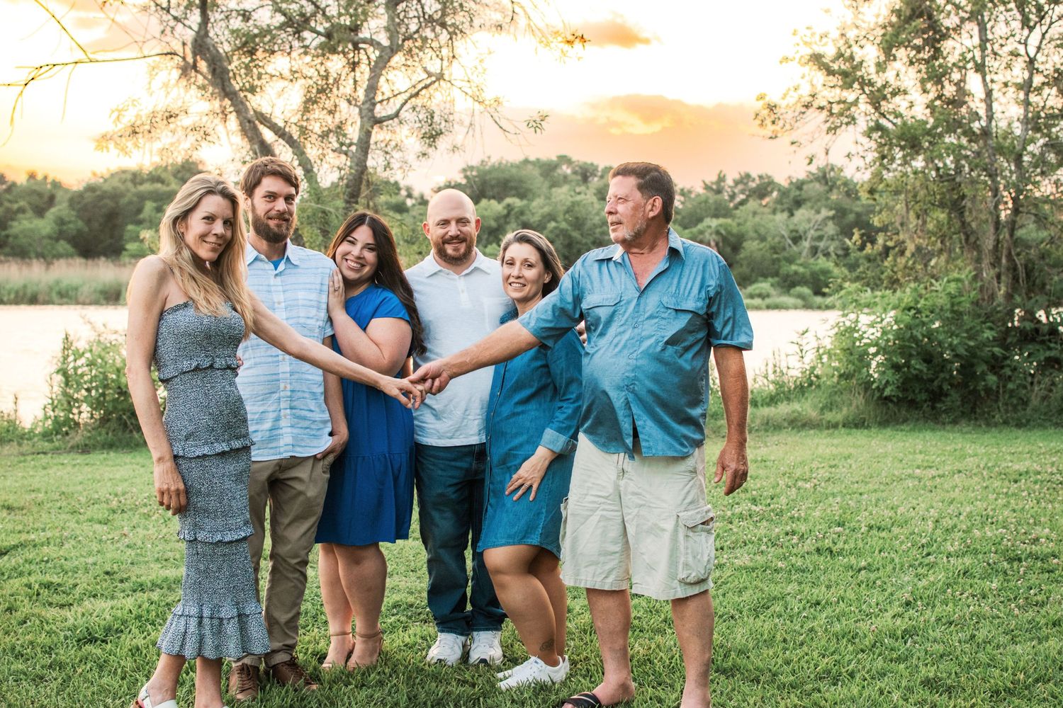 An extended family embraces each other at sunset at a local park