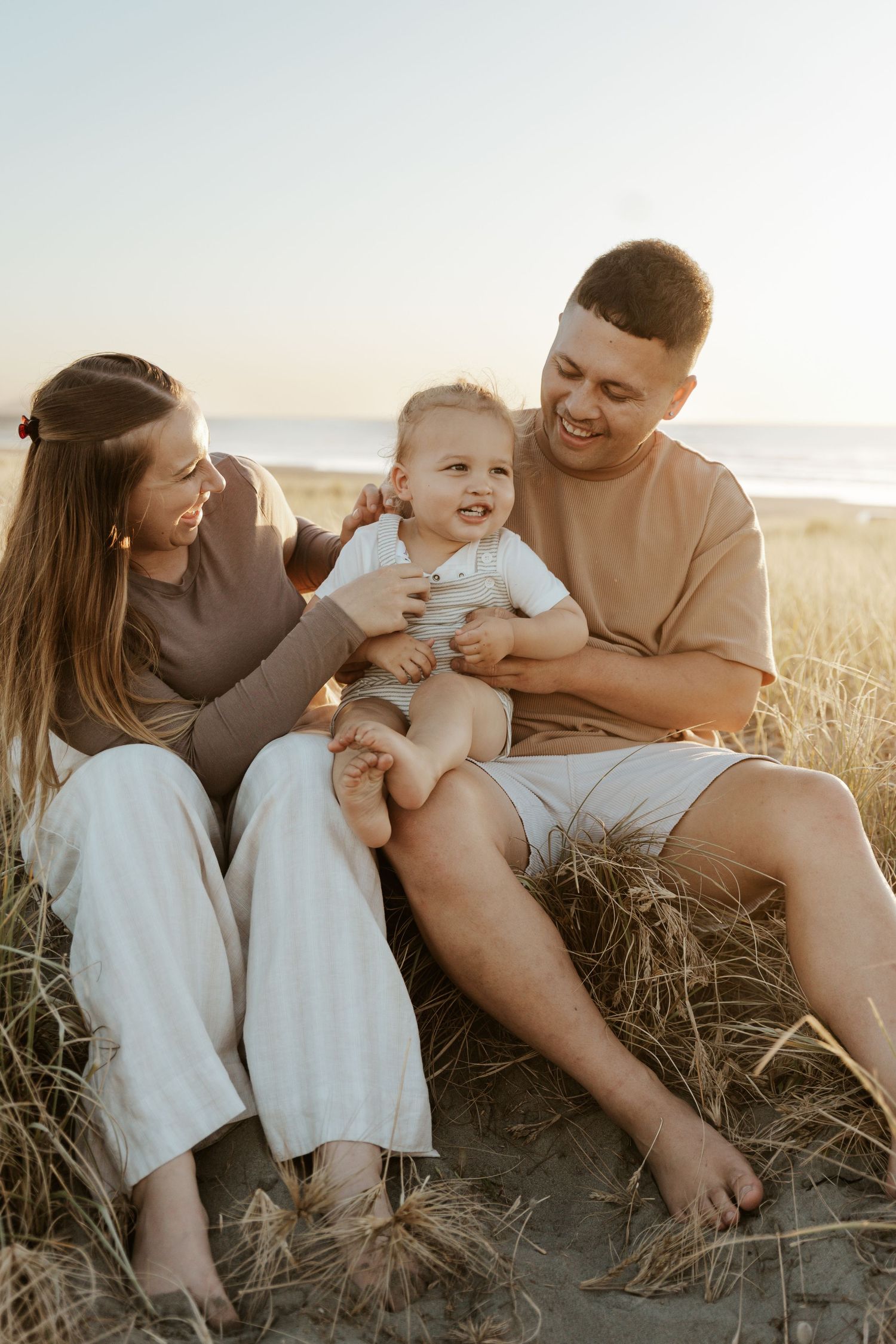 Joyful family moment captured during sunset at beach with tall grass.