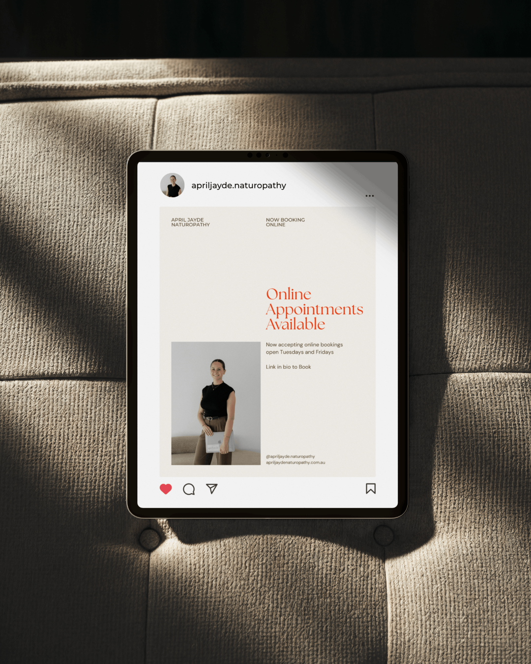 iPad displaying April Jayde Naturopathy Instagram post about online appointments on a beige couch.