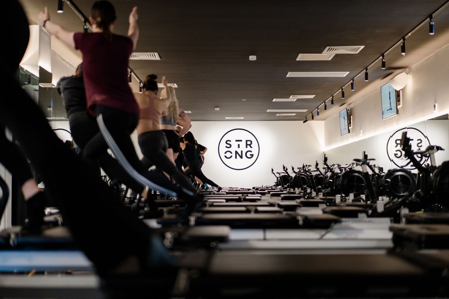 Low angle view of pilates reformer class at STRONG fitness studio with branded wall.