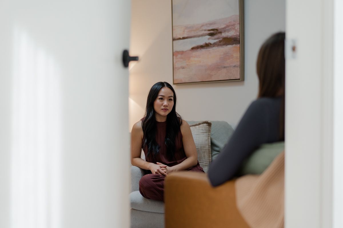 Woman in therapy session listening attentively while seated on white sofa in modern room.