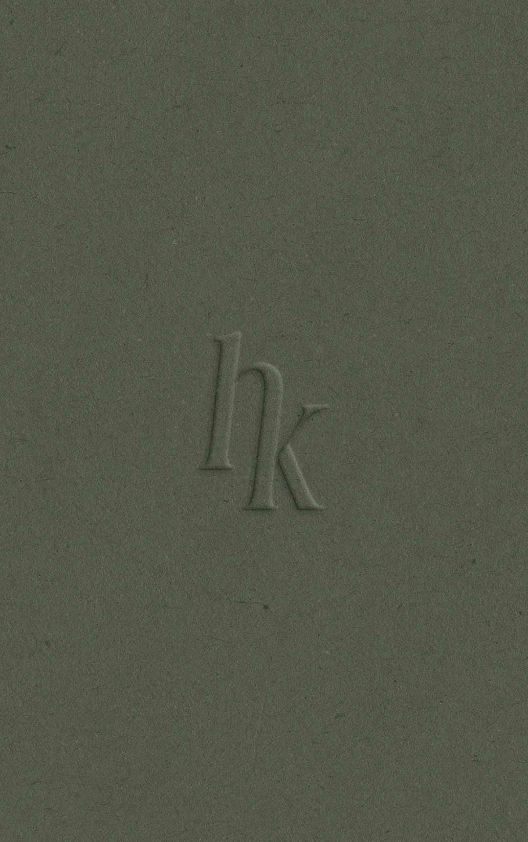 Embossed hk monogram logo on dark olive green textured paper background.