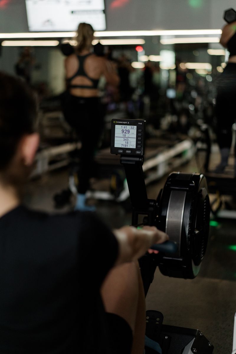 Close-up of a Concept2 rowing machine monitor displaying workout stats in a dark gym setting.