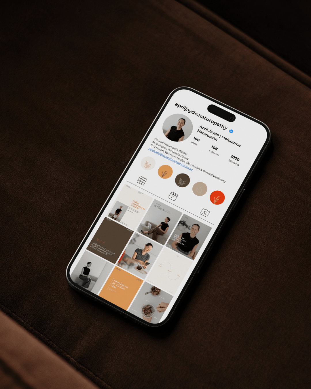 iPhone displaying April Jayde Naturopathy Instagram profile grid with earth tone branded content.