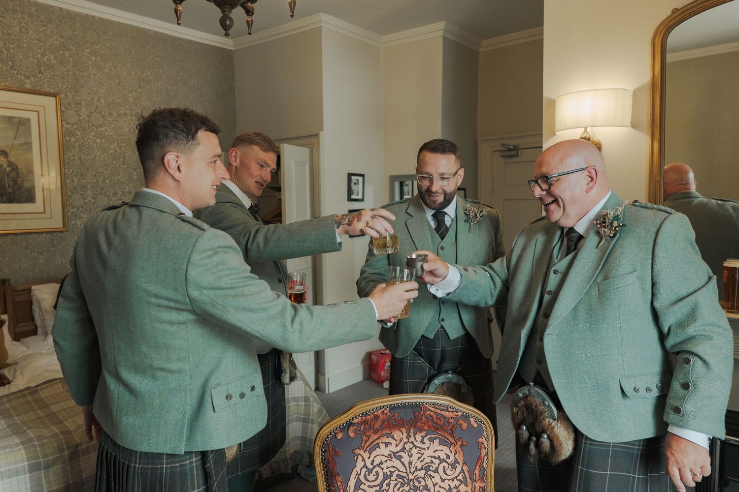 Several people in matching green jackets gather in a formal room while preparing for an event.
