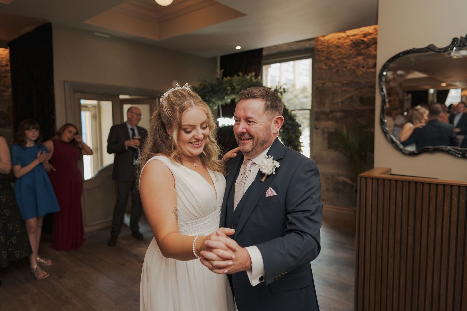 A couple shares a romantic dance moment in an elegant indoor venue with wood paneled walls.