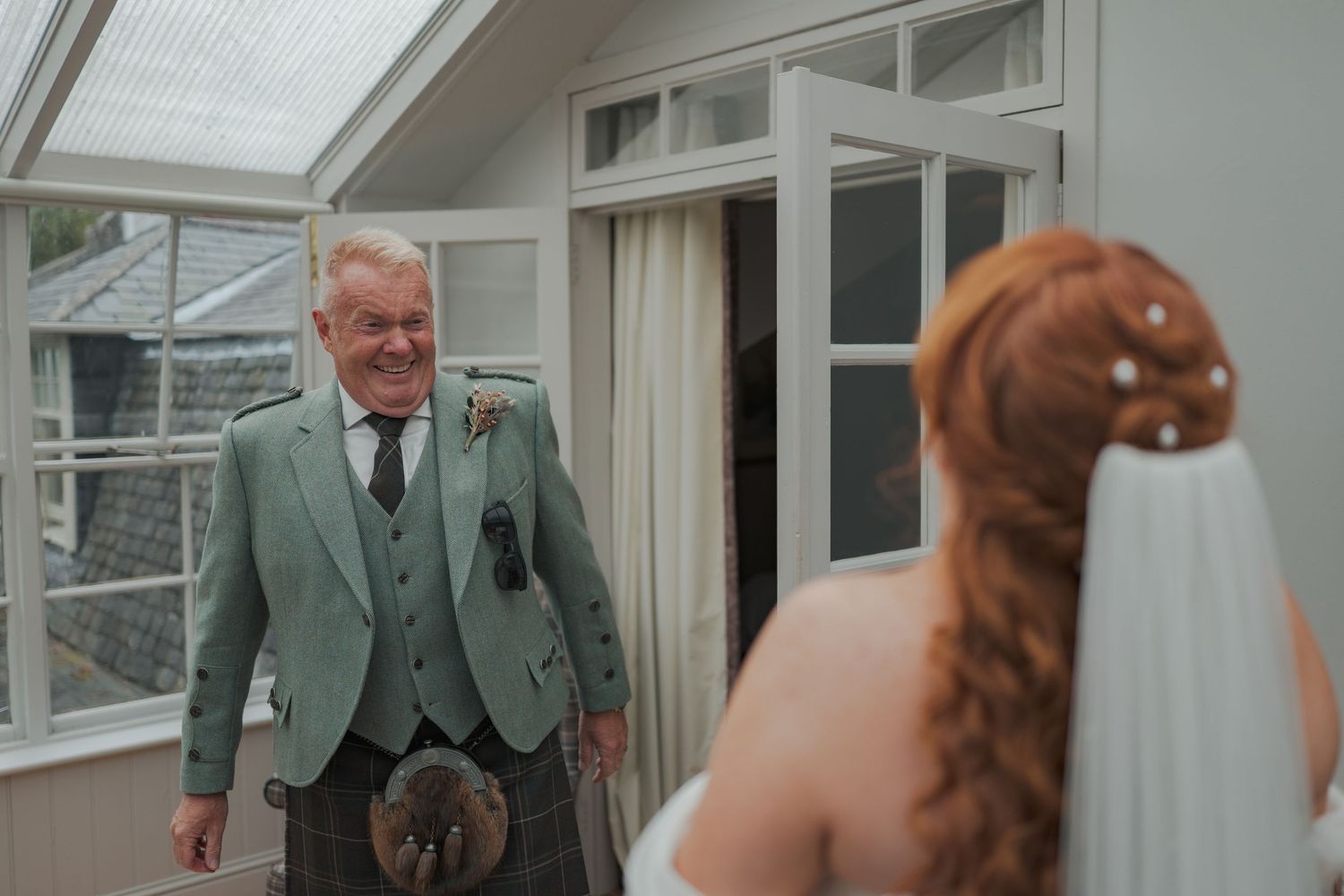 Elegant wedding couple shares intimate moments during their ceremony in a bright sunlit room at Banchory Lodge.