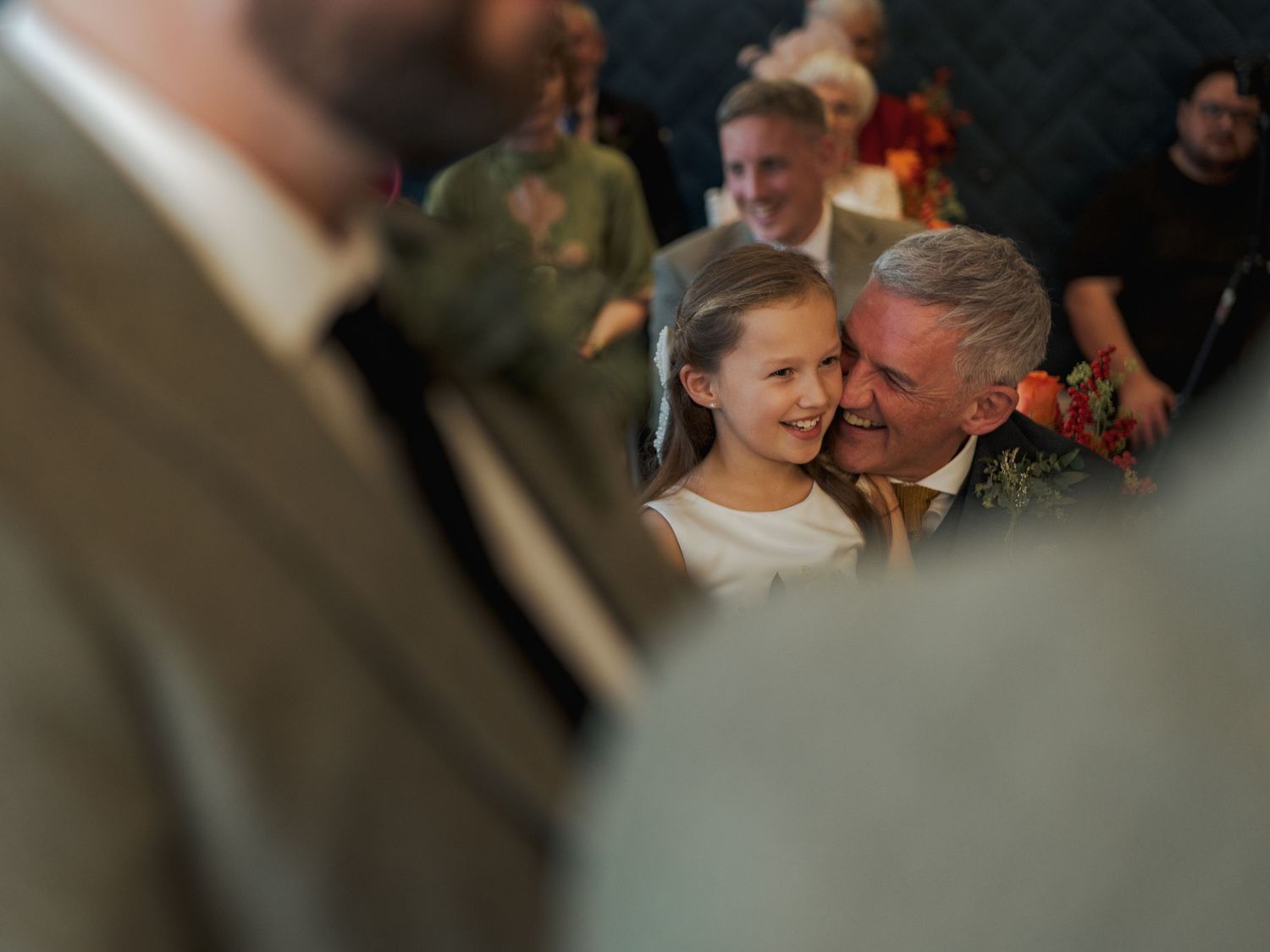 Wedding guests dancing and enjoying themselves at an indoor reception with warm lighting and festive atmosphere.